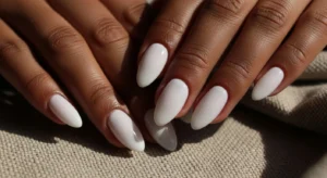 Milky white almond nails on dark skin with glossy finish