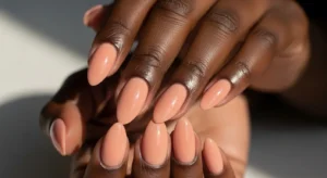 Peach nude almond nails complementing deep skin tone