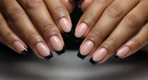 Black French tip nails on dark skin with nude base