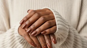 Rich chocolate brown nails on Black woman hands, short square shape, cozy sweater background, neutral aesthetic