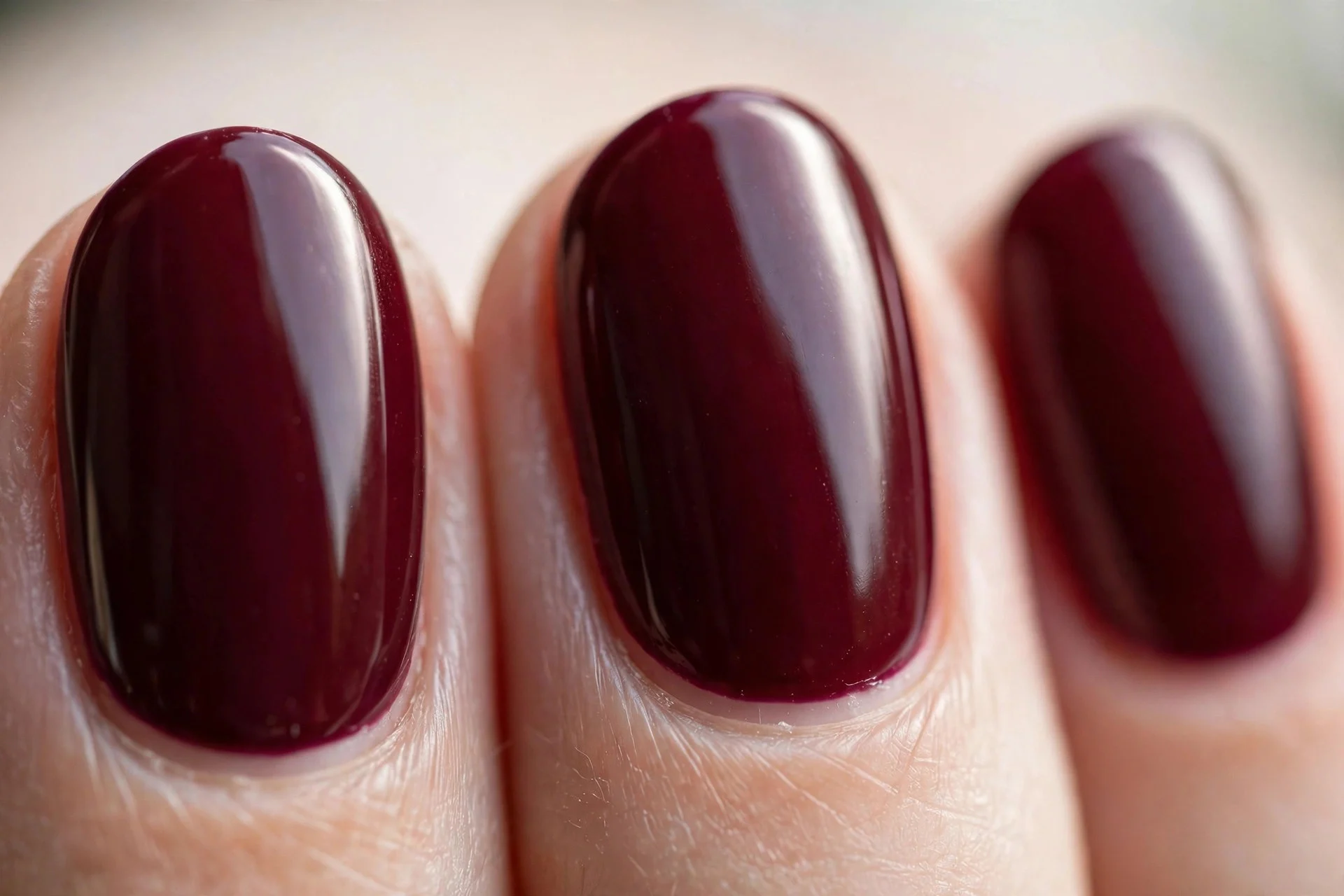 Oval nails in deep burgundy polish with a glossy finish