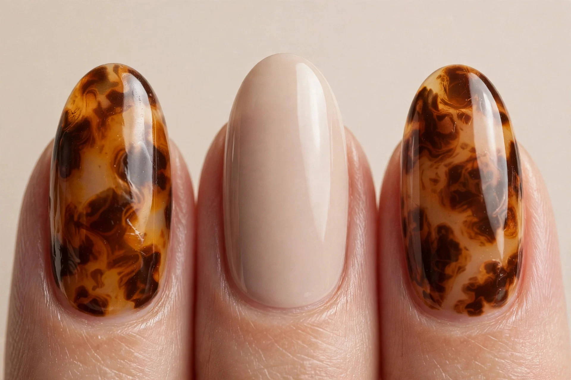 Almond nails with tortoiseshell amber-brown pattern on accent nails, beige background