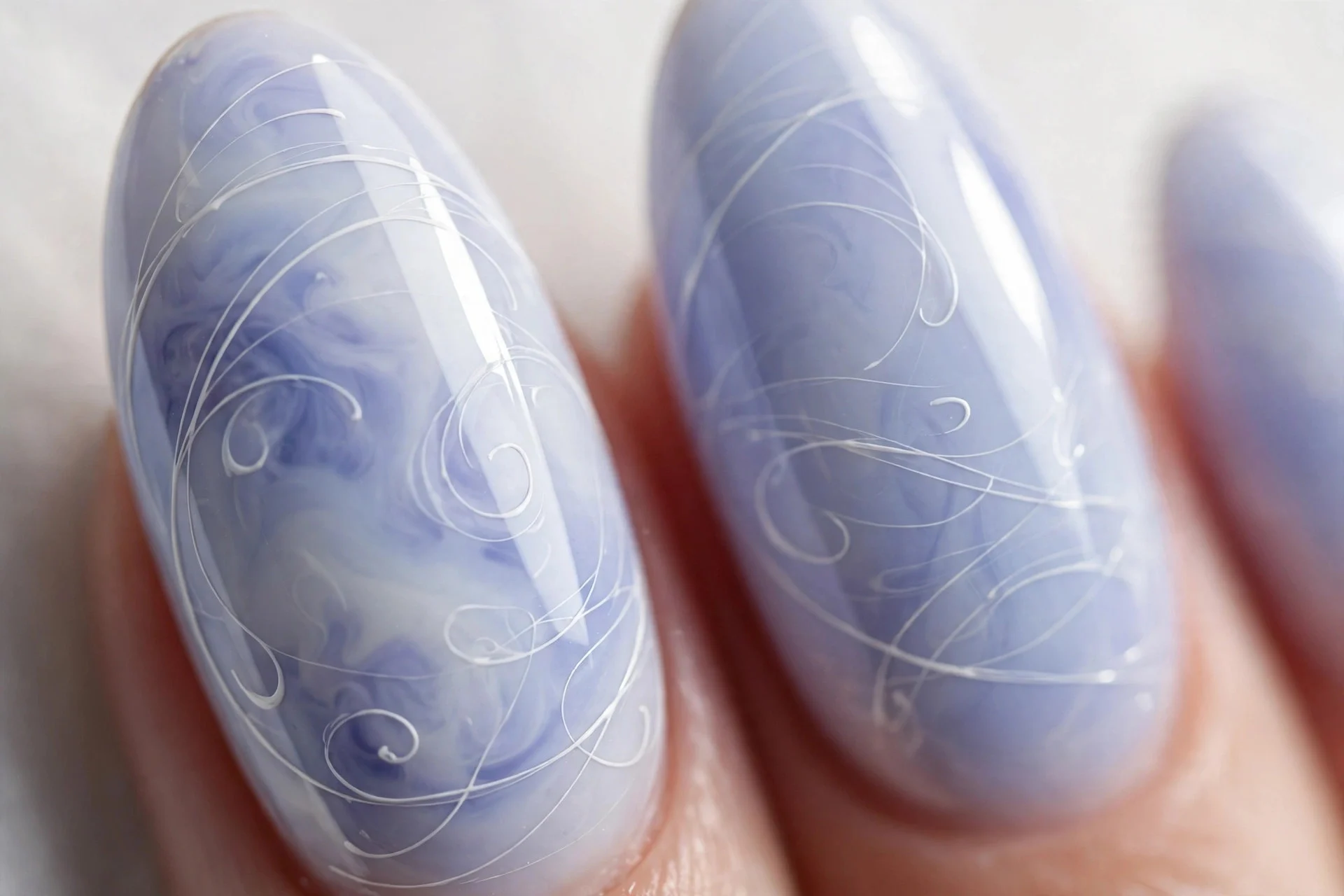 Almond nails with blueberry milk base and thin white hand-painted swirls, glossy, light background