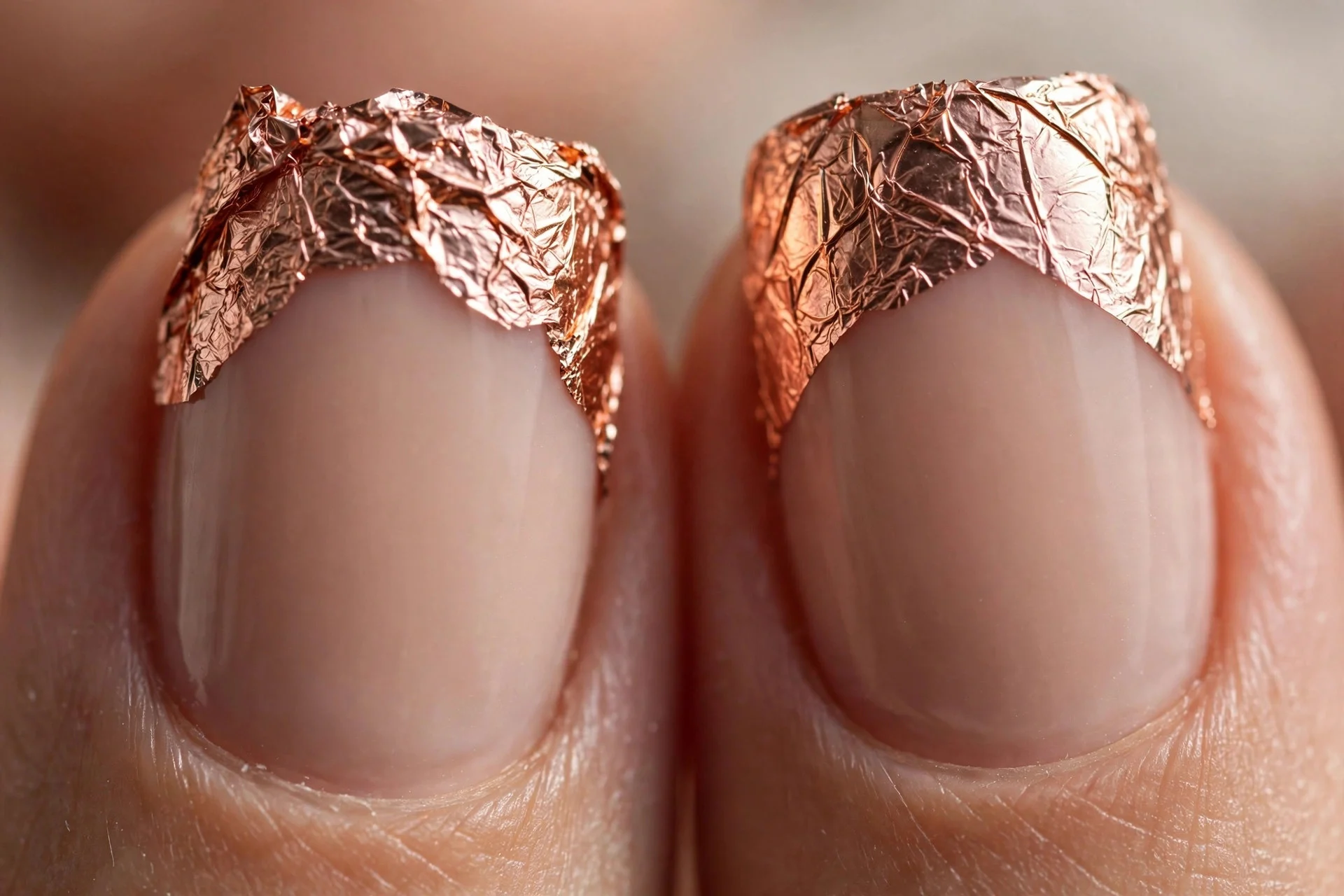Extreme macro of two fingernails with rose-gold foil tips