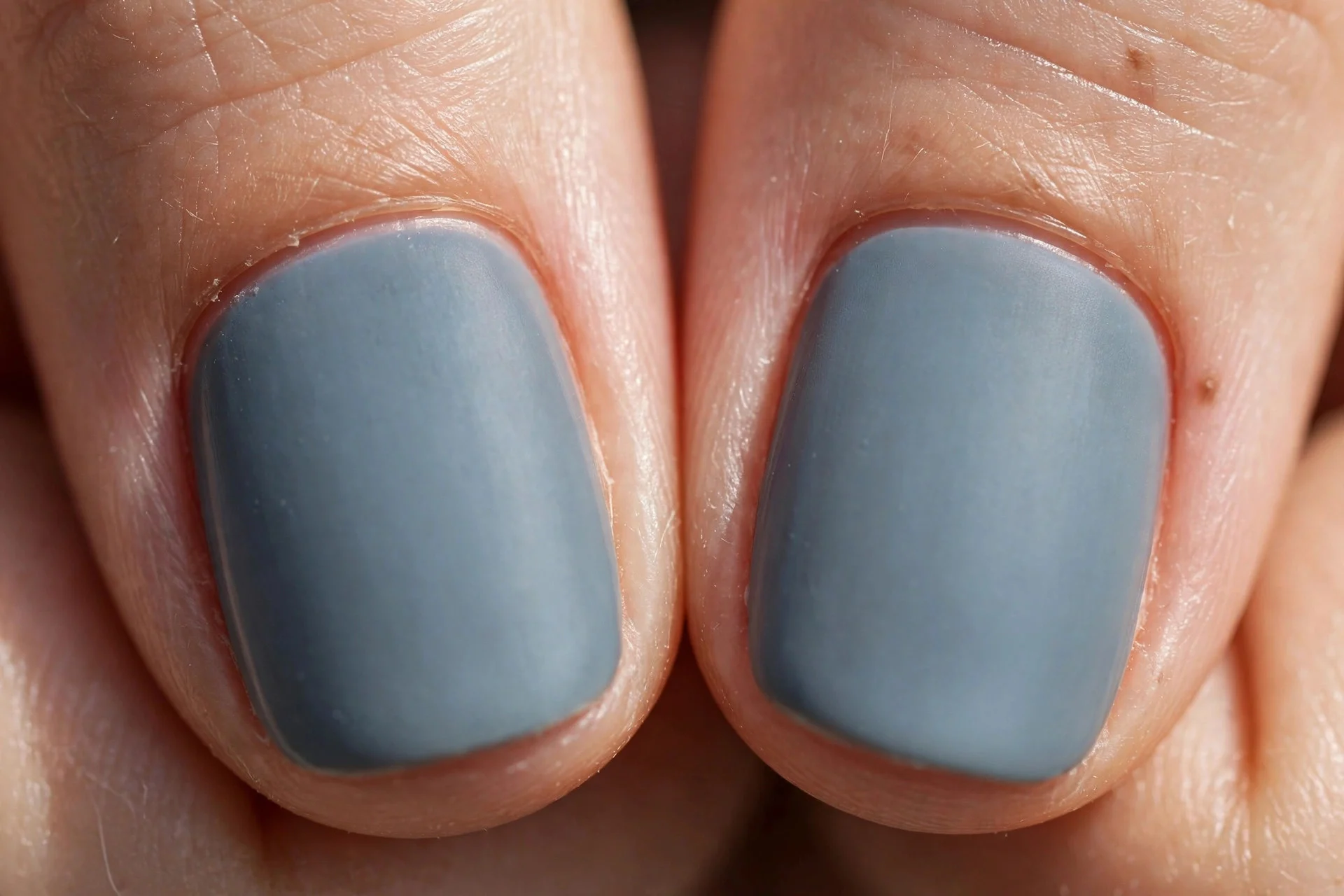 Extreme macro of two fingernails, dusty blue-grey crème polish