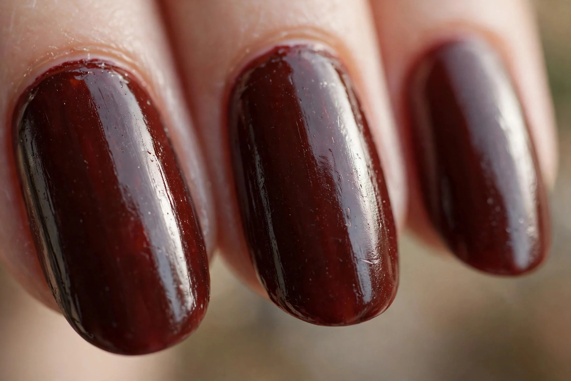 Deep oxblood dark red-brown polish, short almond nails, glossy