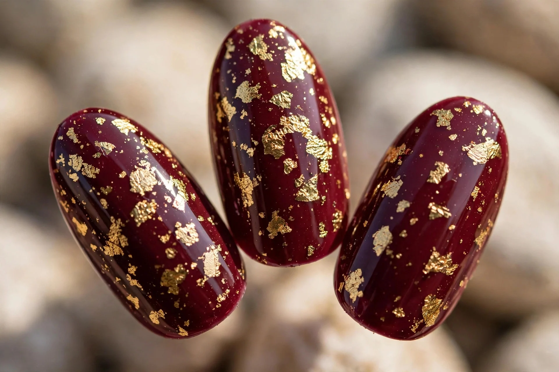 Burgundy nails with gold foil flakes, medium almond, glossy