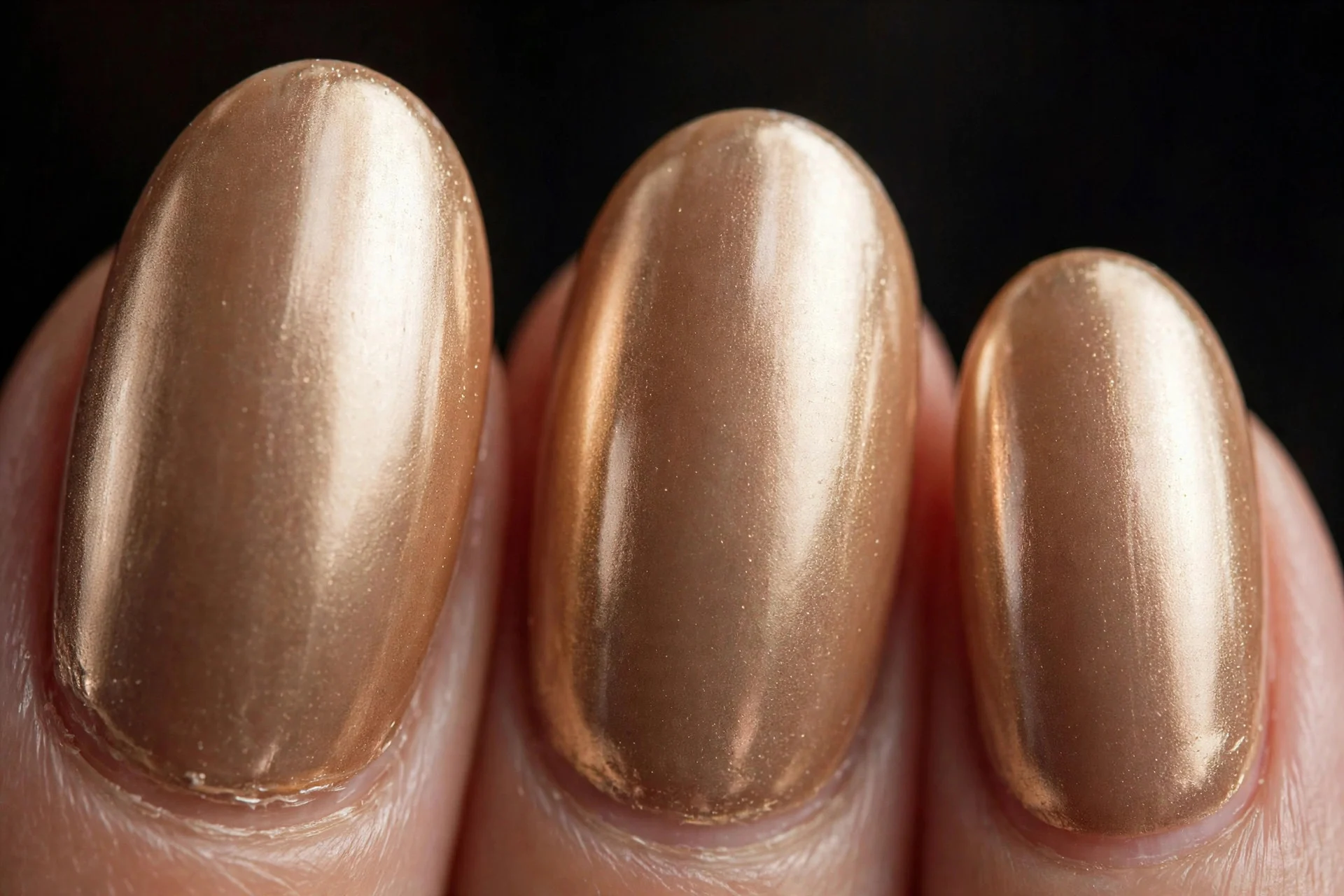 Oval nails in caramel with champagne chrome finish, dark background