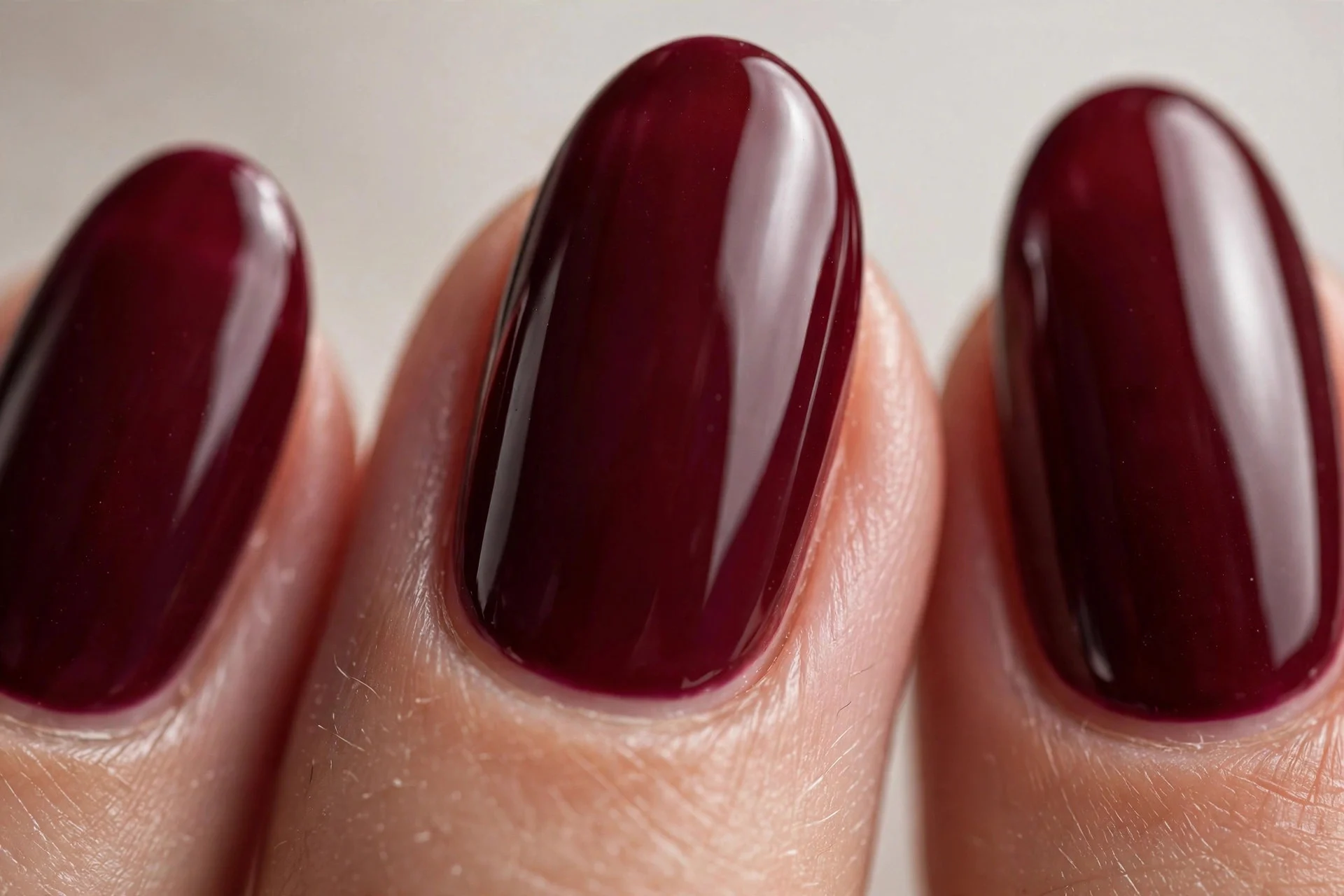 Almond nails in deep cherry wine crème, glossy, neutral background