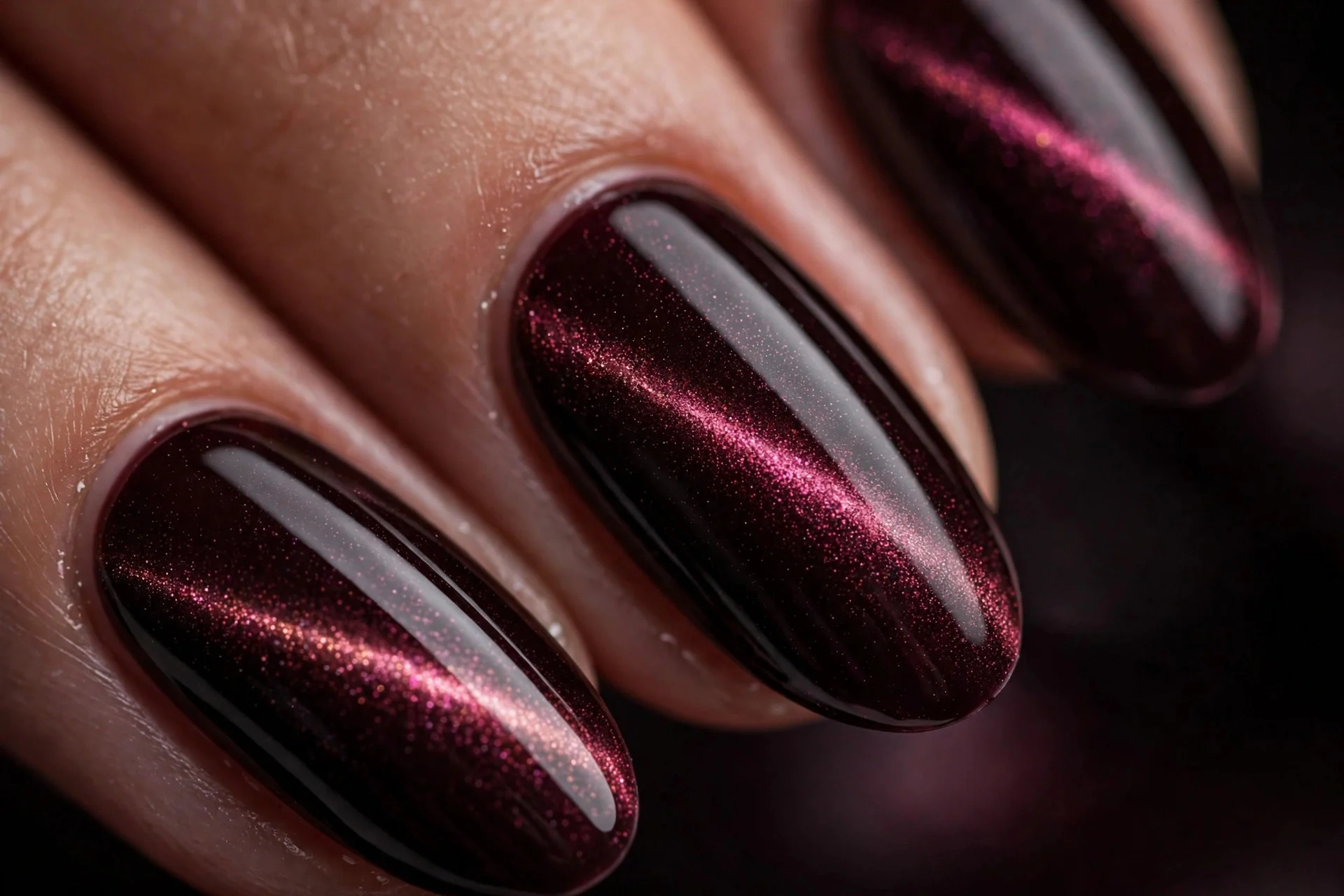 Almond nails in black cherry with magnetic cat-eye shimmer line, glossy, dark background