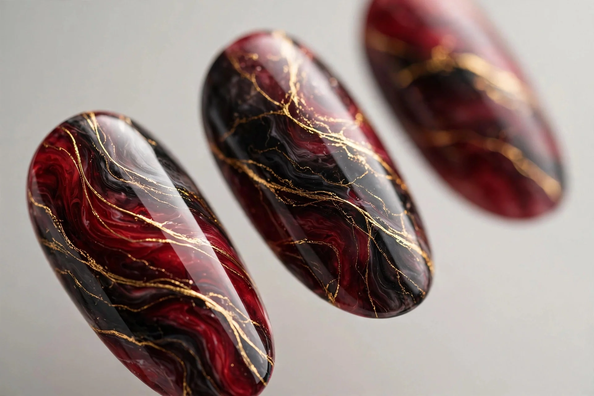 Almond nails with cherry and black marble veining with gold threads, glossy, neutral background