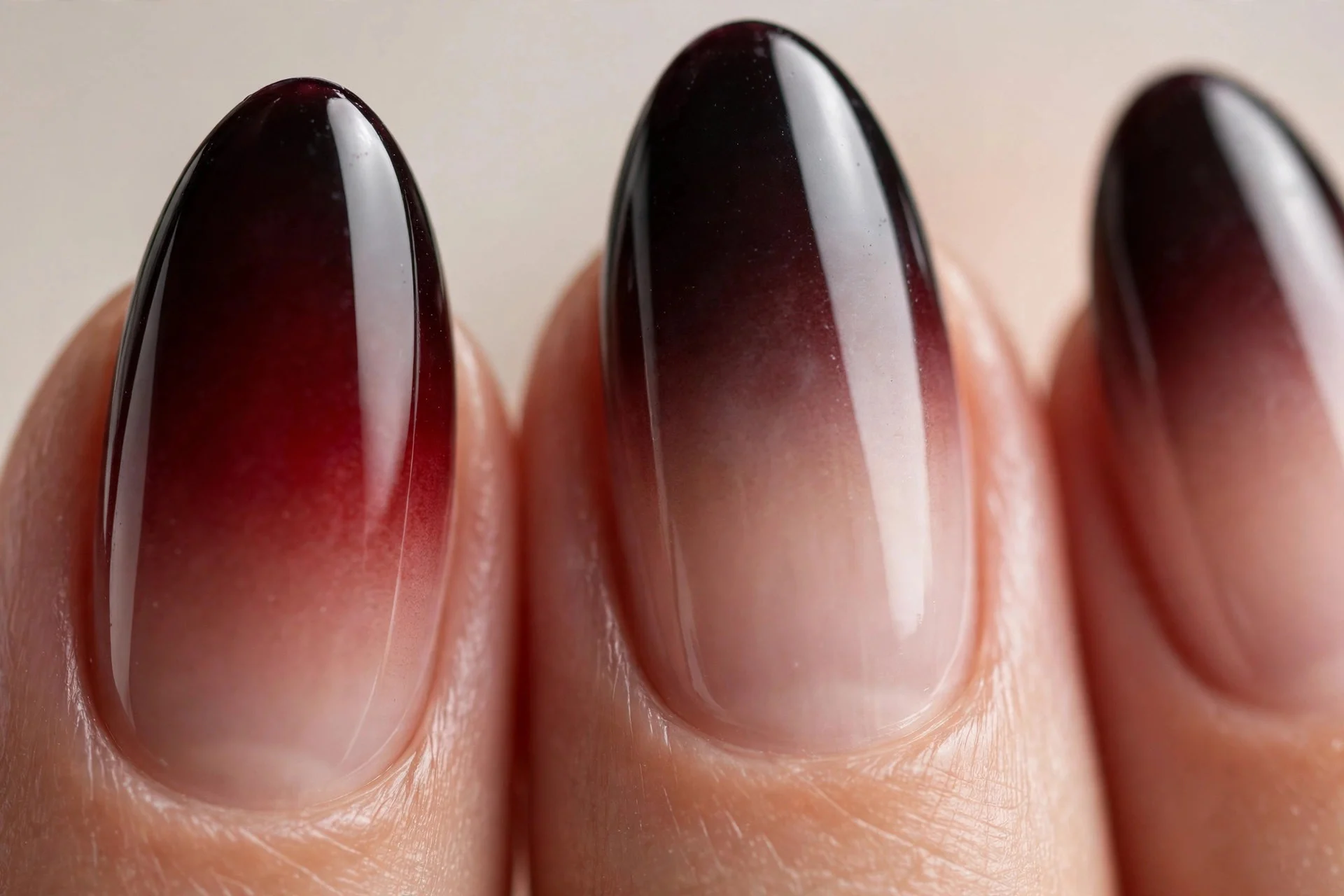 Almond nails with black cherry fading to sheer nude ombre, glossy, neutral background