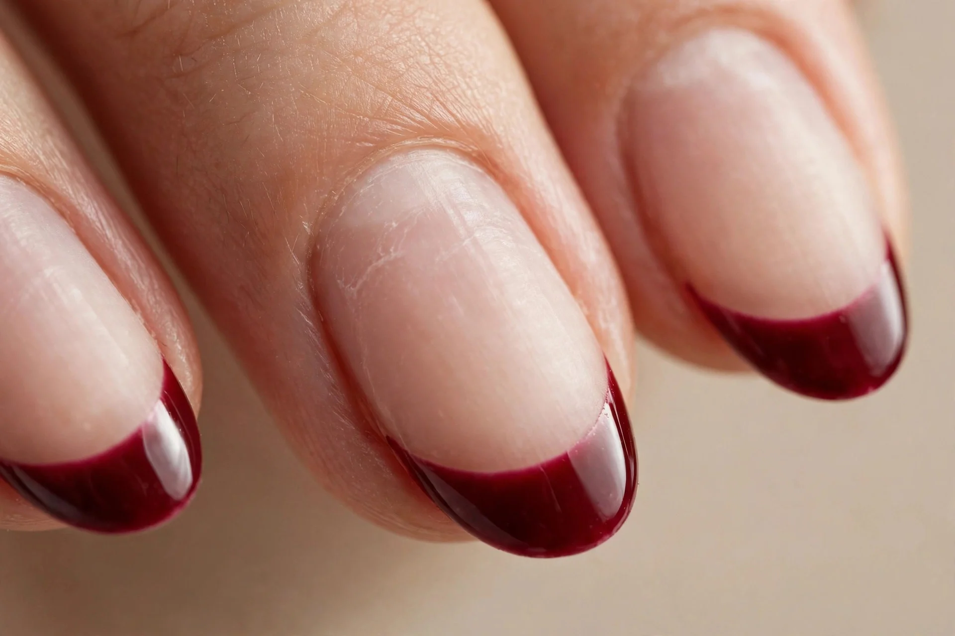 Almond nails bare with cherry wine painted only on tips, glossy, beige background
