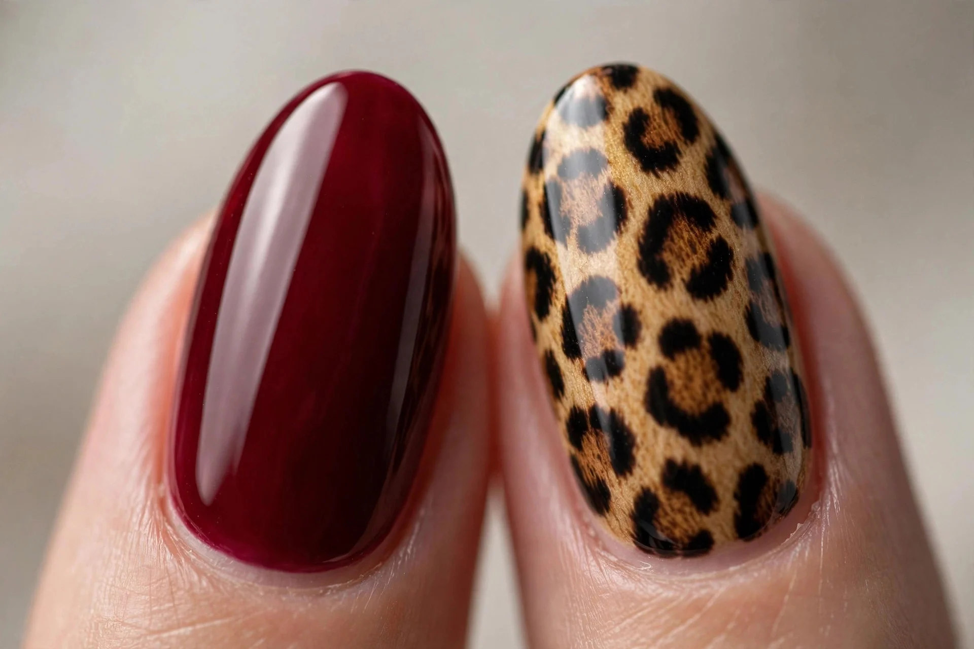 Almond nails in cherry wine with one leopard-print accent nail per hand, glossy, neutral background