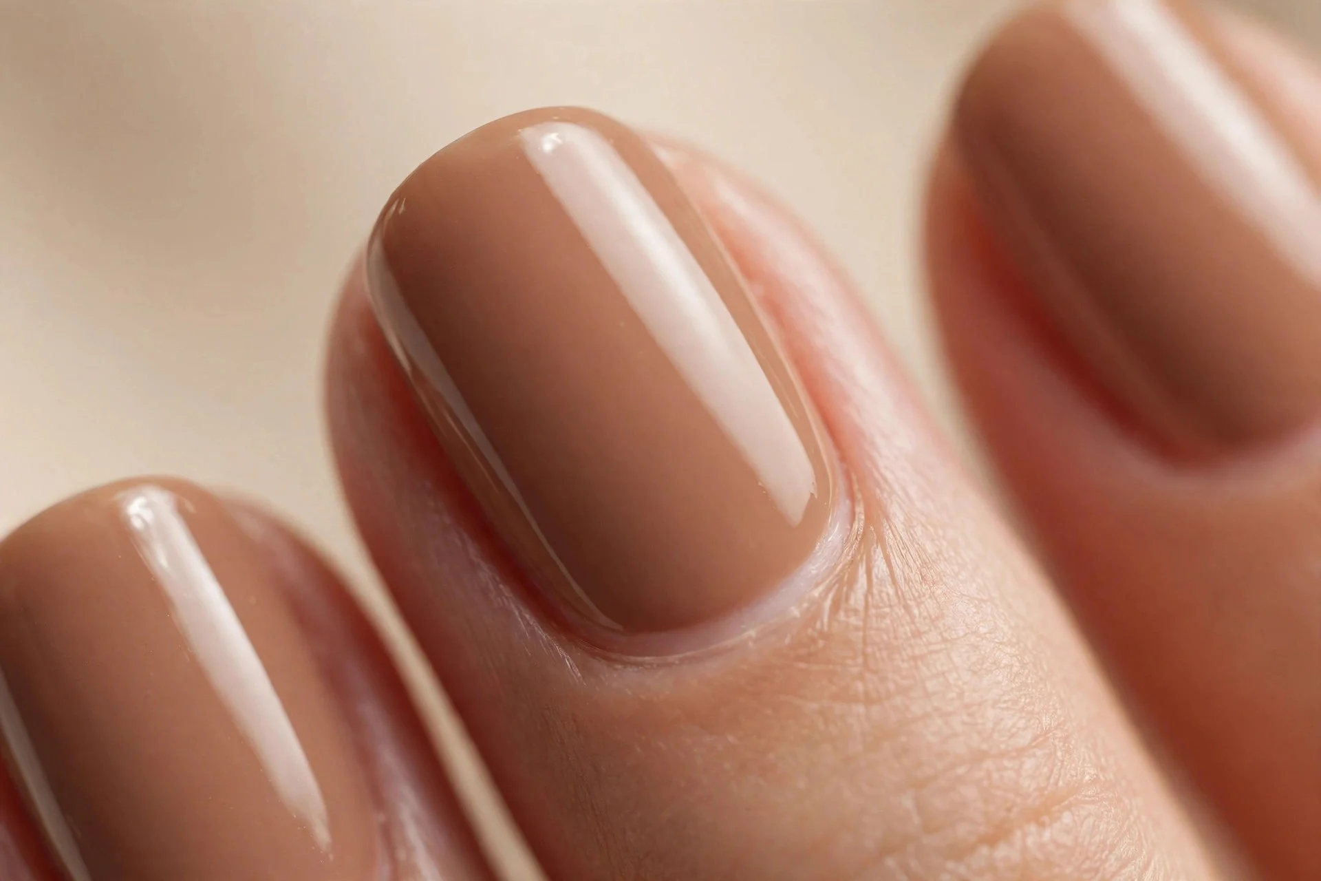 Short almond nails in milky cinnamon-brown creme polish, glossy, beige background