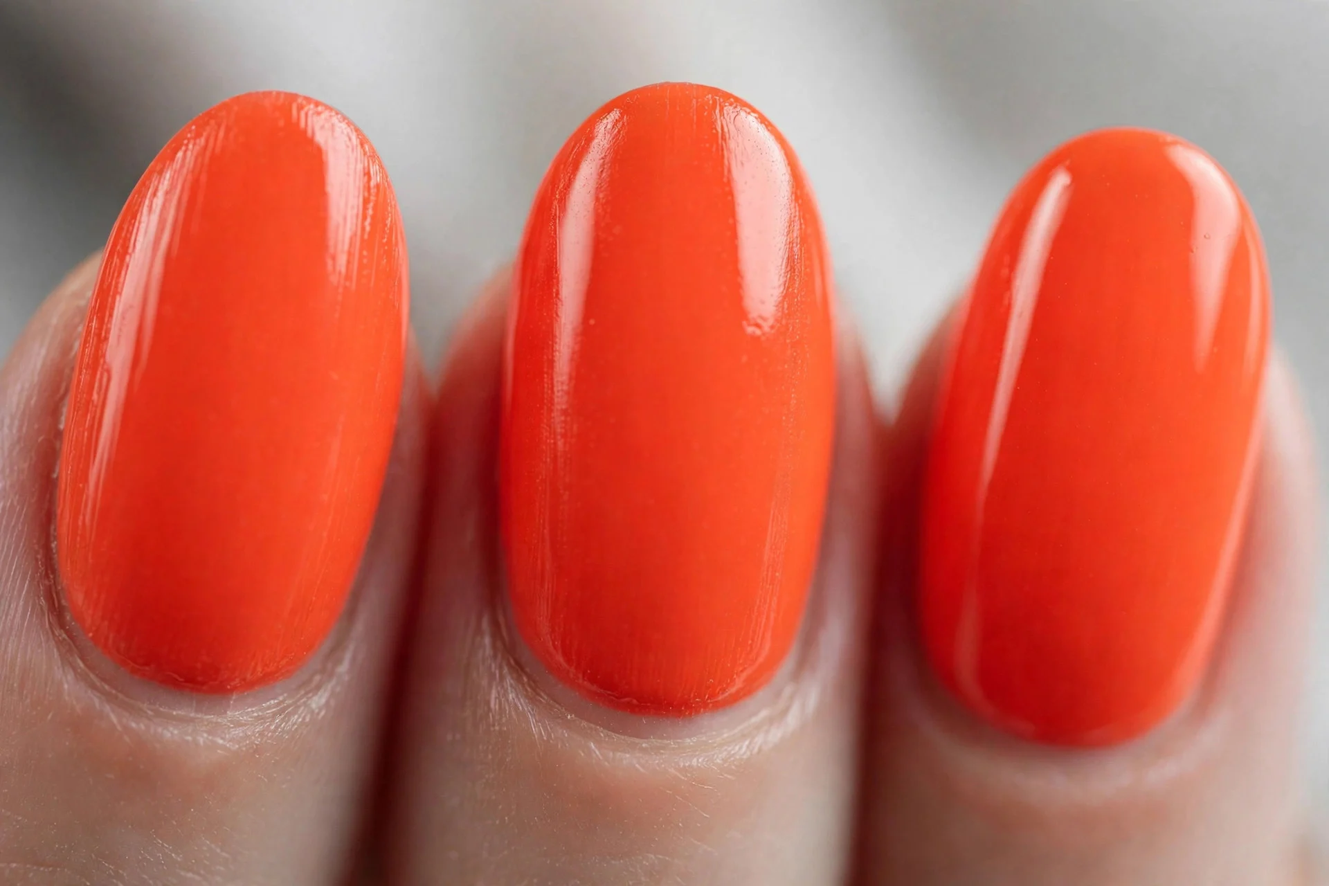 Vivid tangerine-coral polish, medium almond nails, glossy