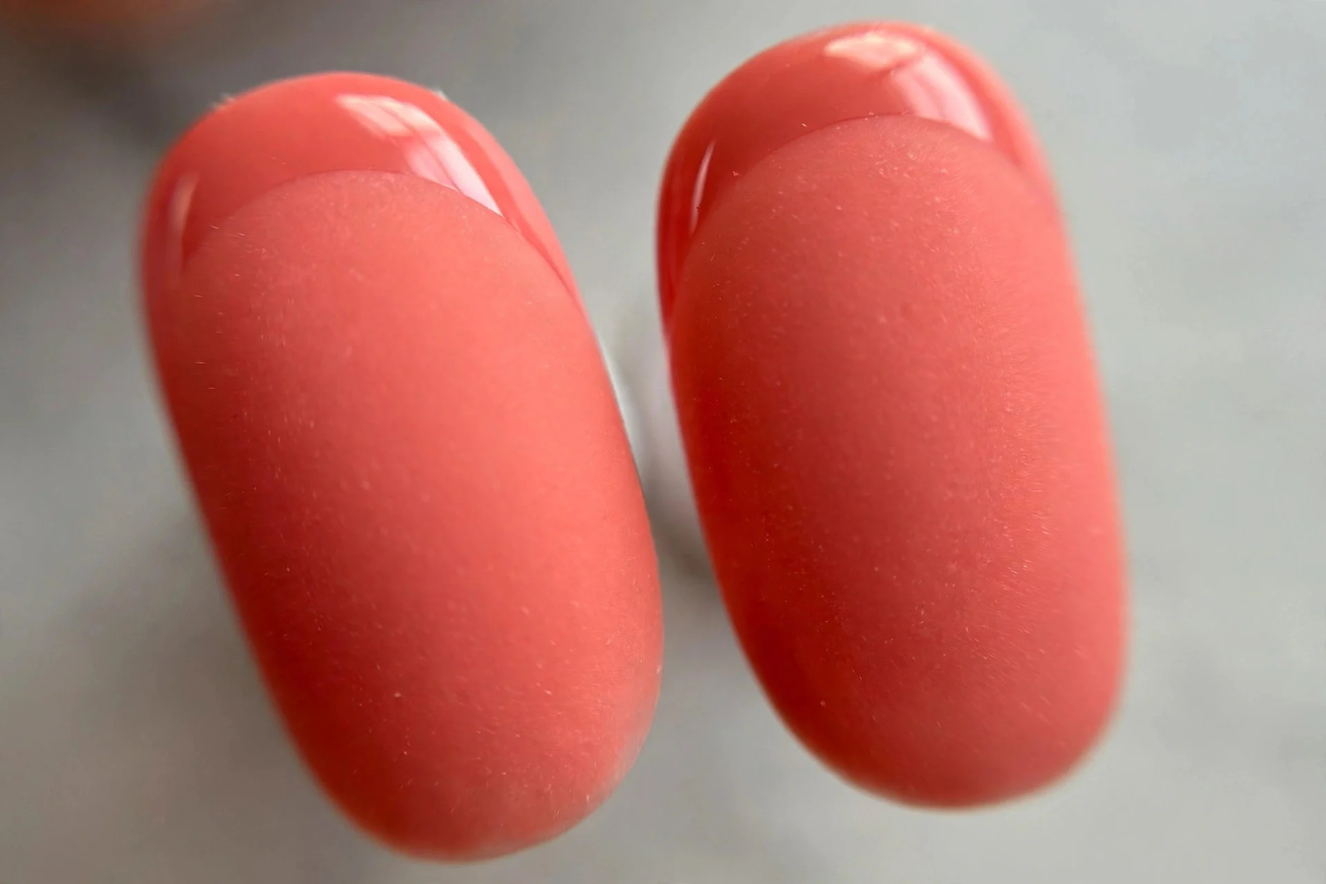 Matte coral nails with glossy coral French tips, oval nails