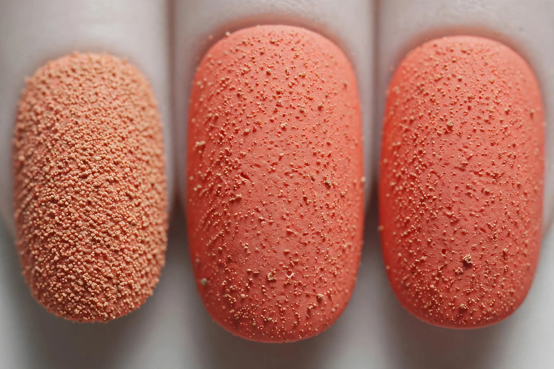 Coral nails with fine sandy grain texture, short oval nails