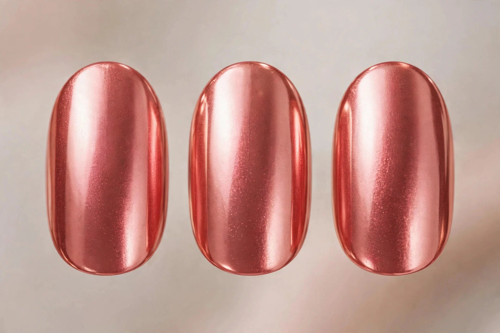 Coral nails with rose-gold chrome finish, medium oval, metallic pink