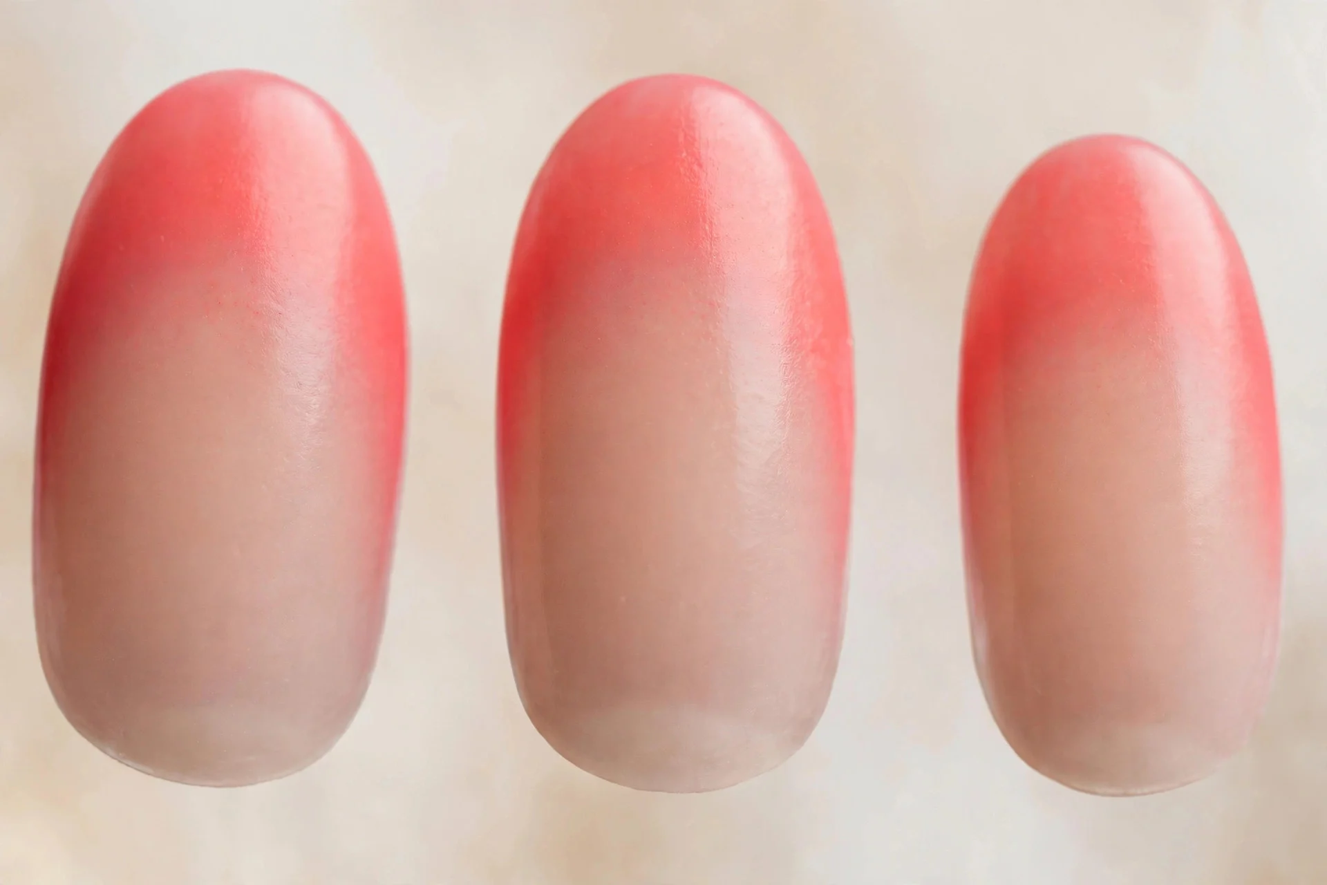Coral aura nails fading to sheer nude base, oval nails
