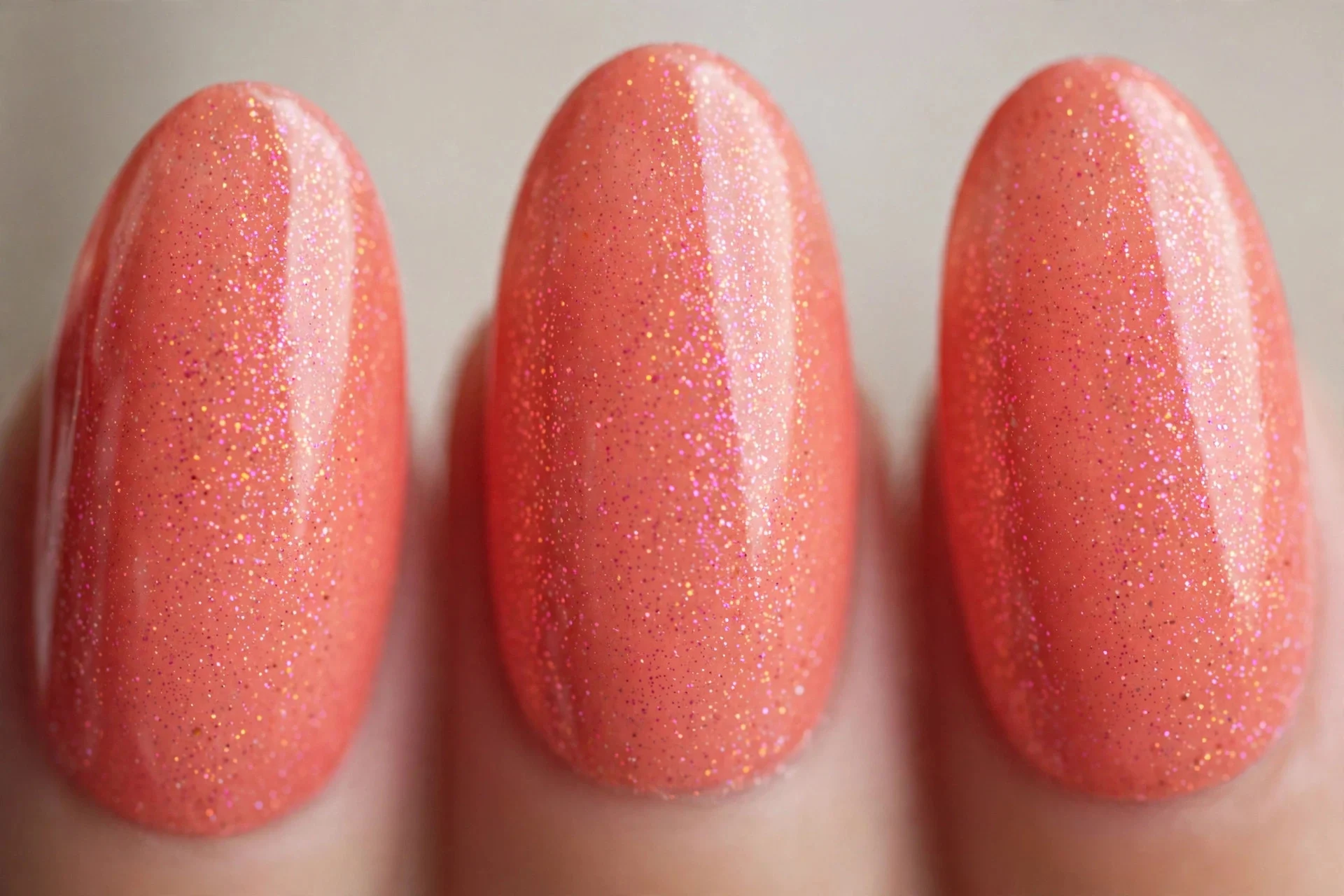 Coral nails with pink and peach micro-shimmer, medium almond