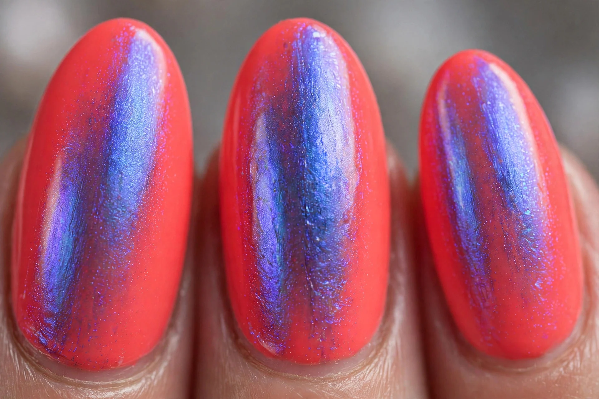 Bright coral nails with iridescent blue-violet shimmer, almond nails