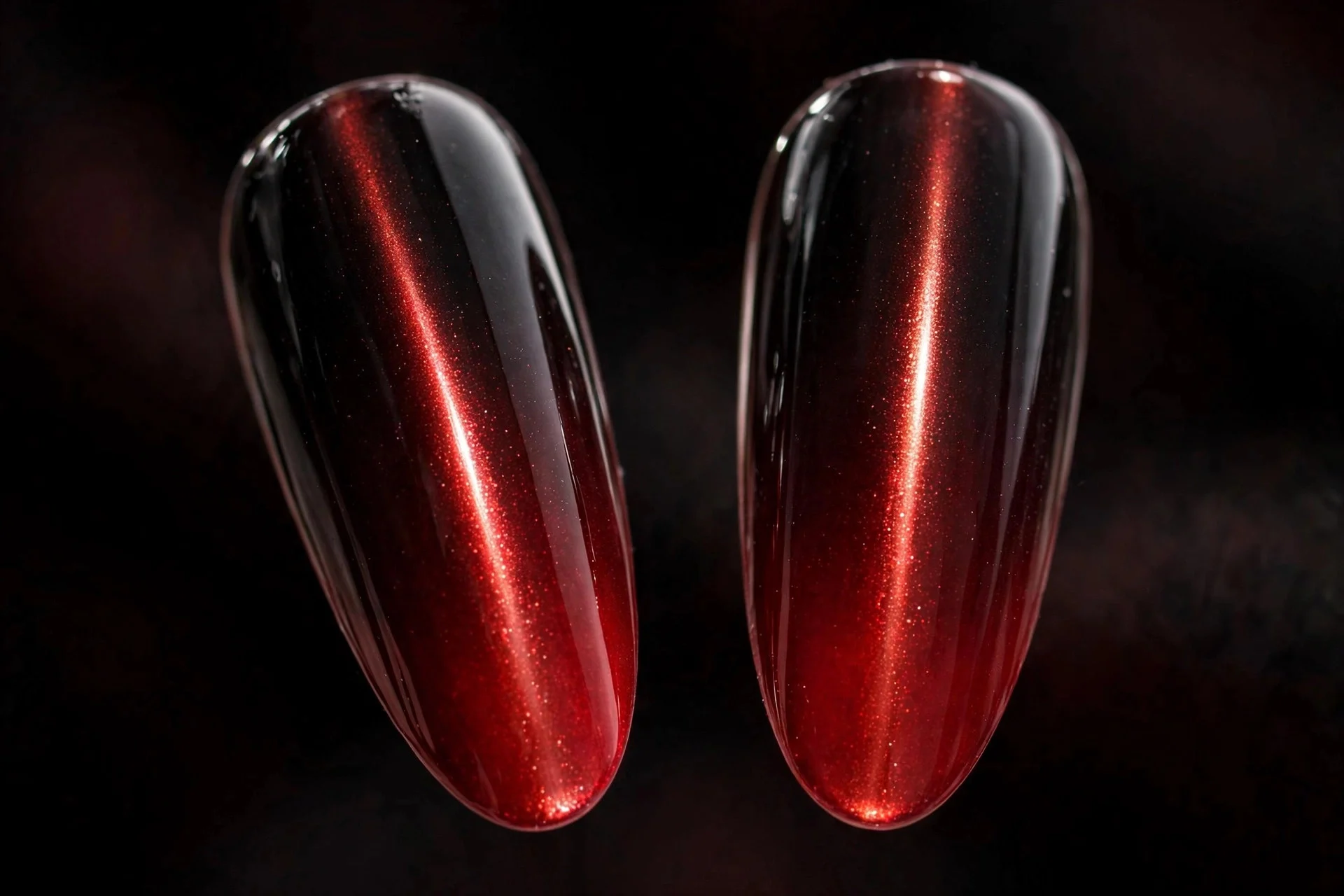 Extreme macro of two long fingernails with black-to-red ombré cat-eye blending into a glowing magnetic fade