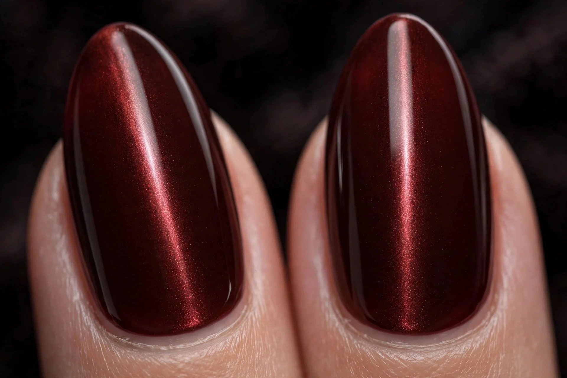 Extreme macro of two medium almond fingernails in oxblood cat-eye gel with a sharp vertical band, timeless elegant finish