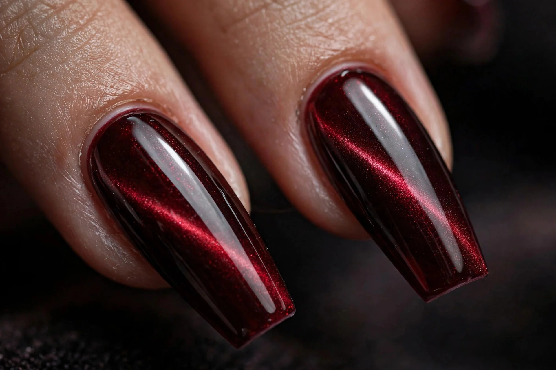 Extreme macro of two long coffin fingernails in noir red cat-eye gel with a wet-look glass finish, ultra dark glossy