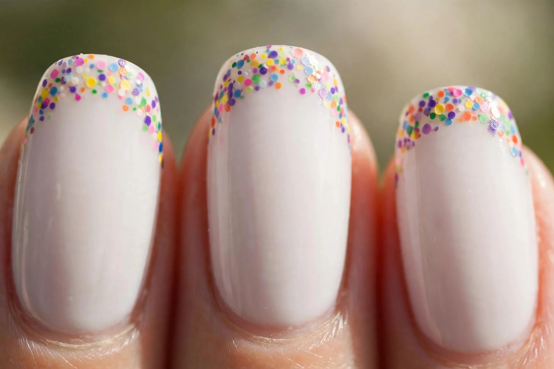 milky white nails with tiny colourful confetti dots on the tips