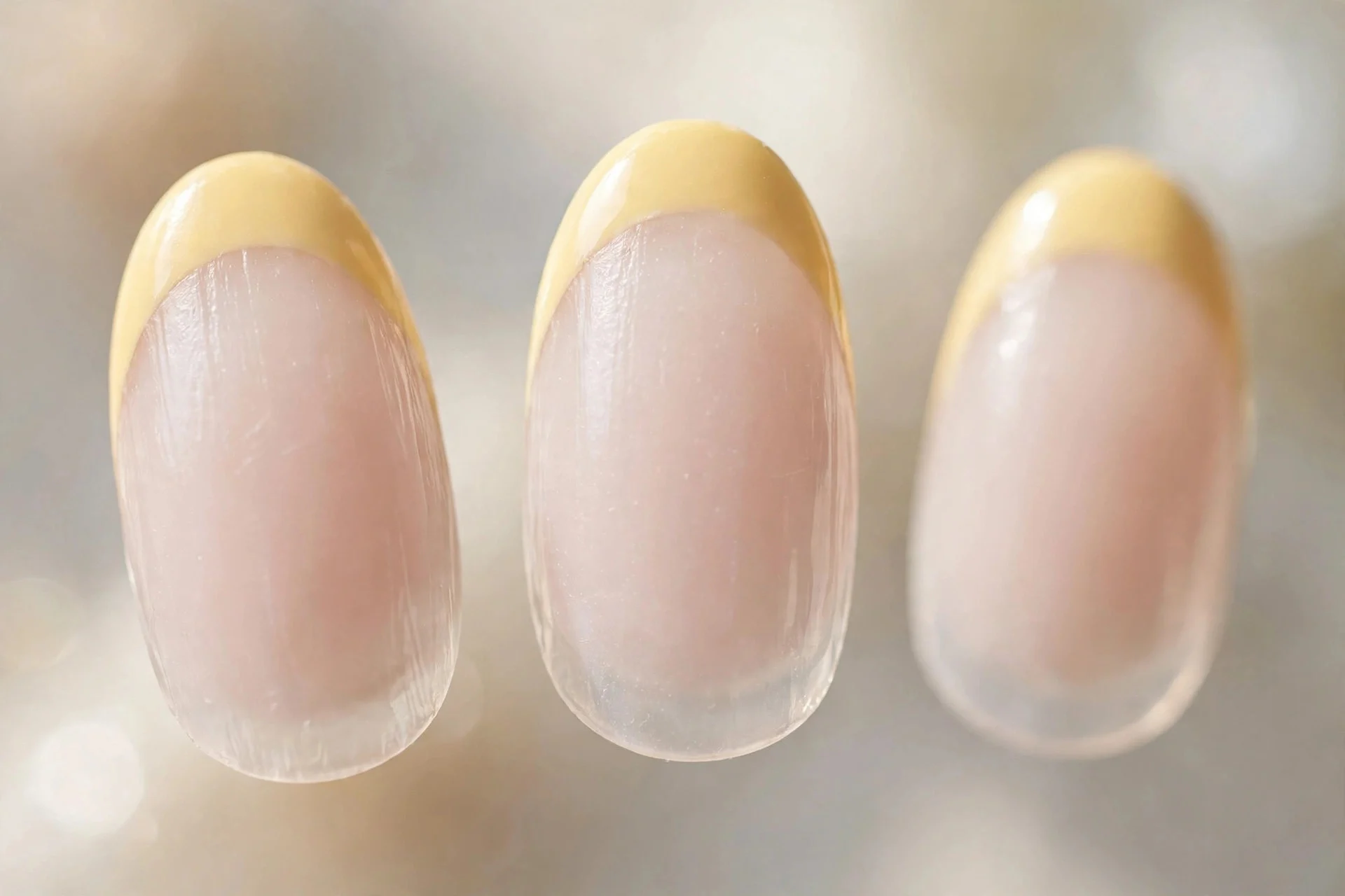 Butter yellow French tips on milky sheer base, almond nails