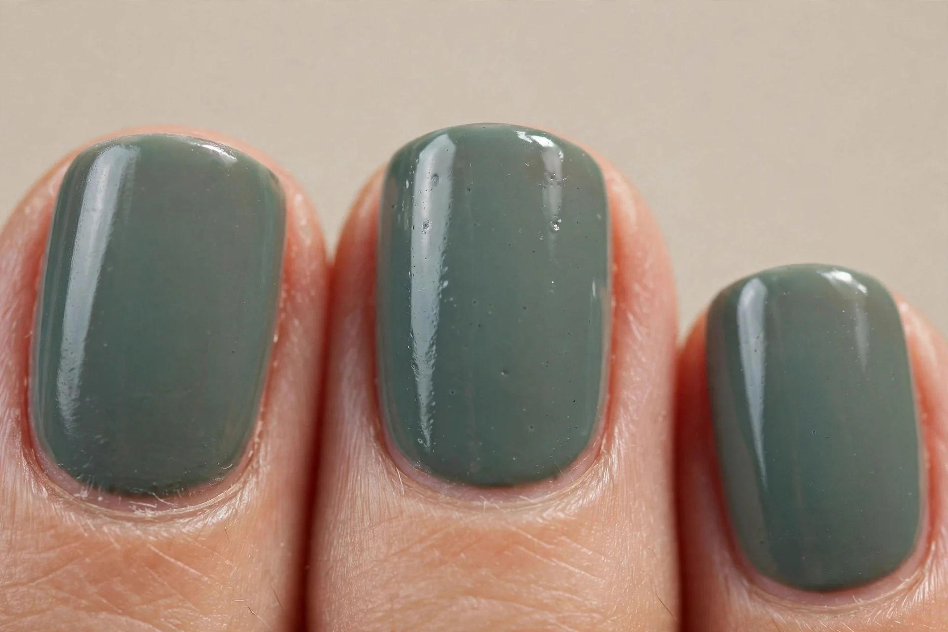 Dusty greyed emerald, short rounded-square nails.