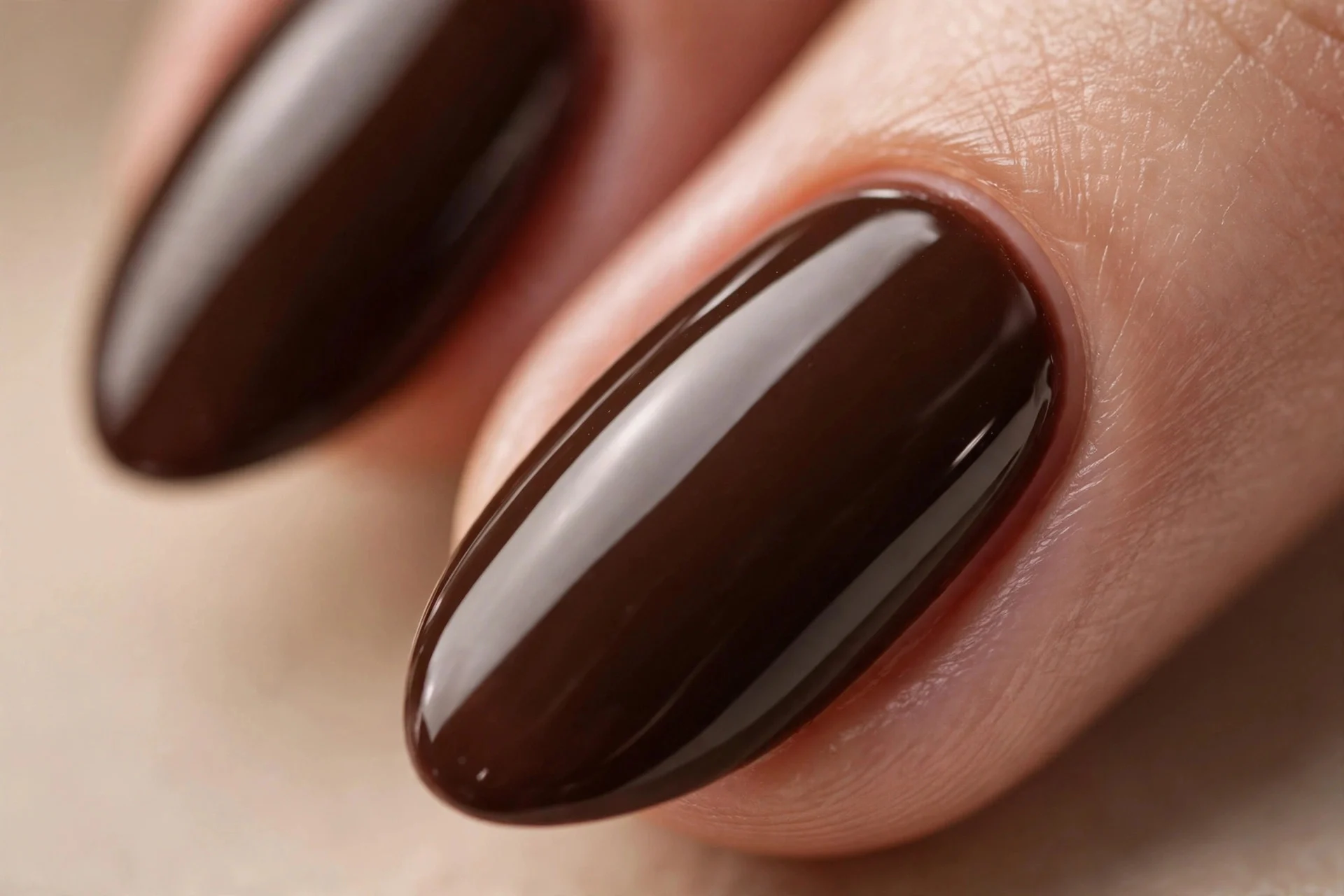 Almond nails with a solid deep espresso cream polish, glossy, beige background