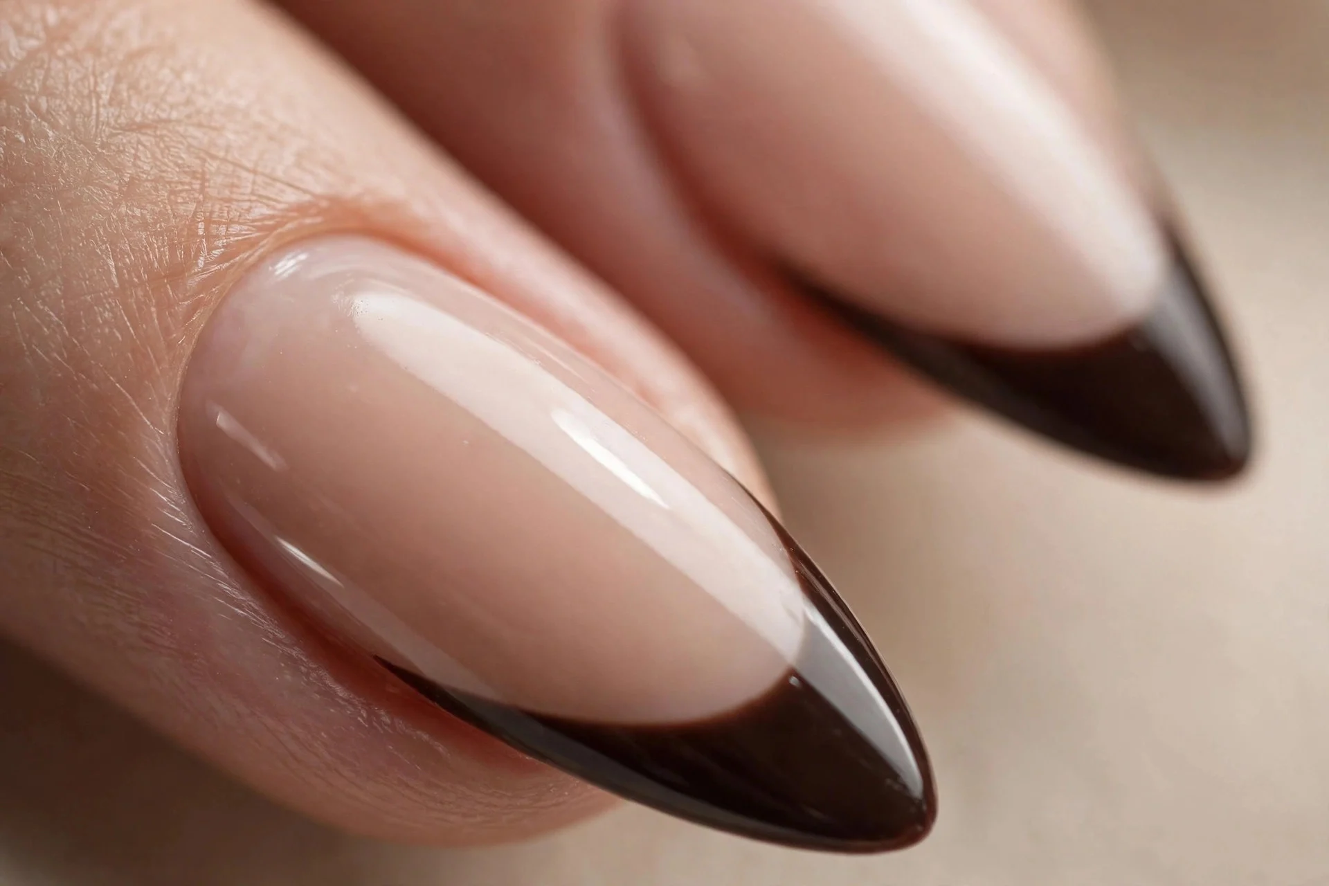 Almond nails with a nude base and deep espresso French tips, glossy, beige background