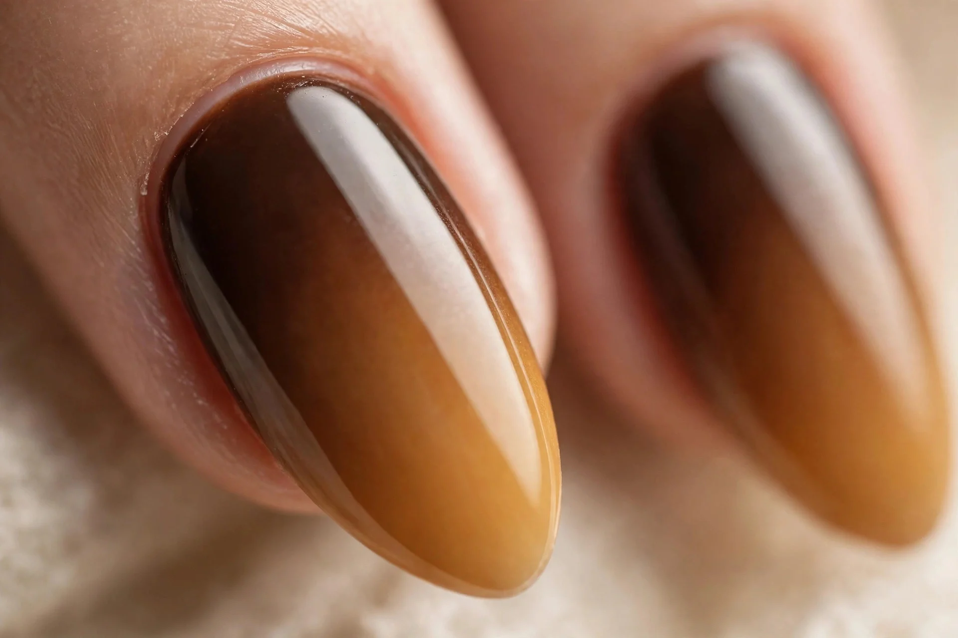 Almond nails with espresso-to-caramel ombre gradient, glossy, beige background