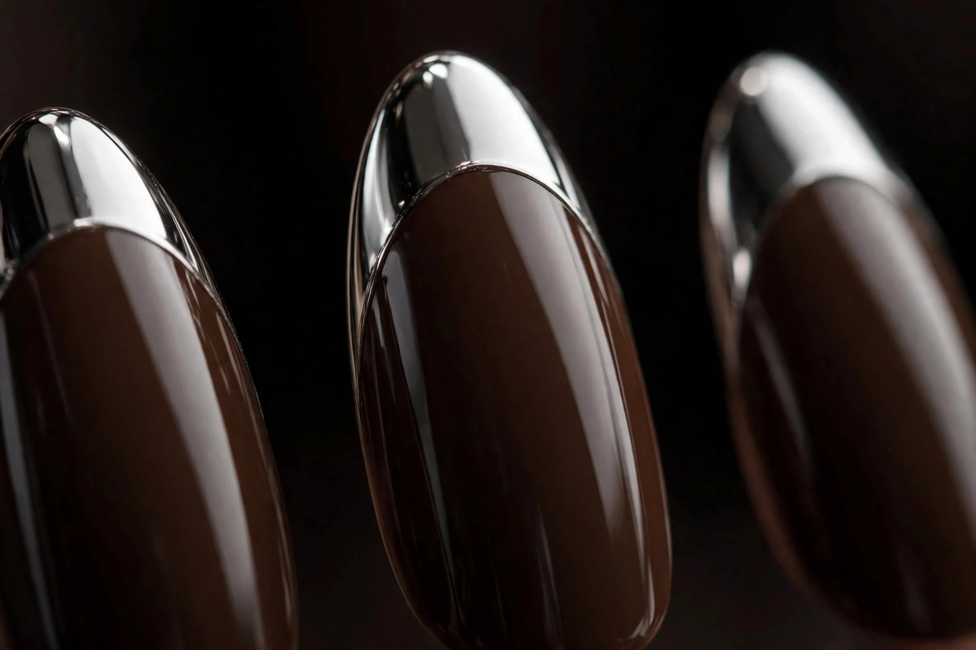 Almond nails with espresso base and mirrored chrome tips, glossy, dark background