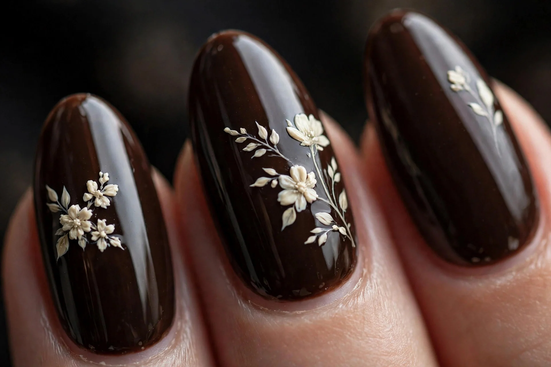 Almond nails with hand-painted cream florals over deep espresso, glossy, dark background