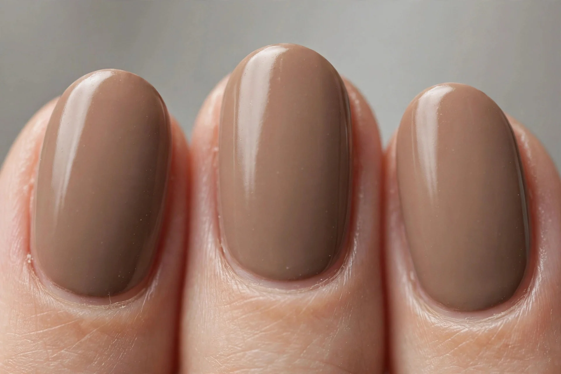 Oval nails in warm mushroom taupe cr&egrave;me polish, soft grey background