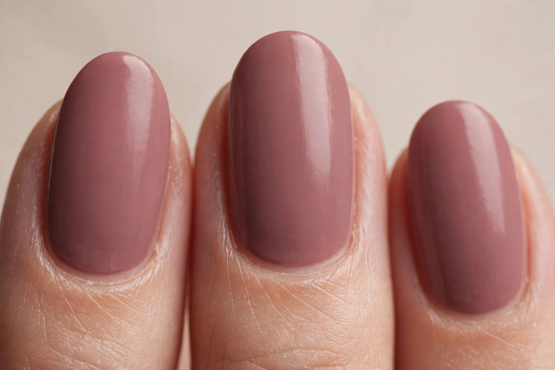 Short almond nails in warm mauve dip powder, neutral background