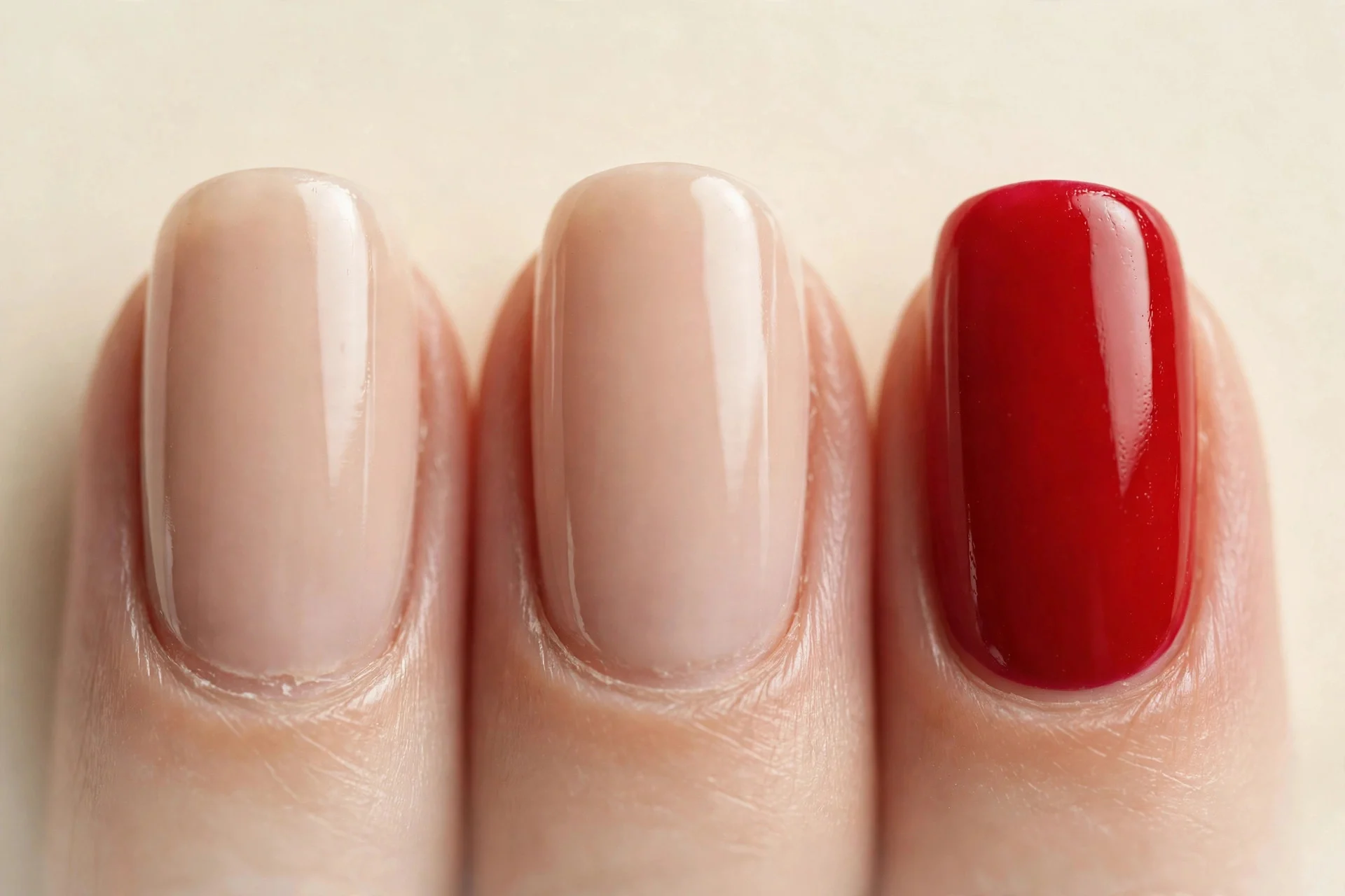 Nude nails with classic red accent on ring fingers, cream background