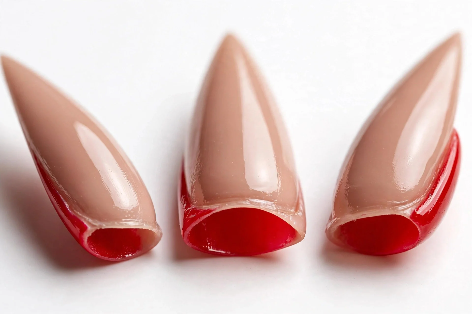 Stiletto nails with red painted undersides visible, nude tops, glossy, white background