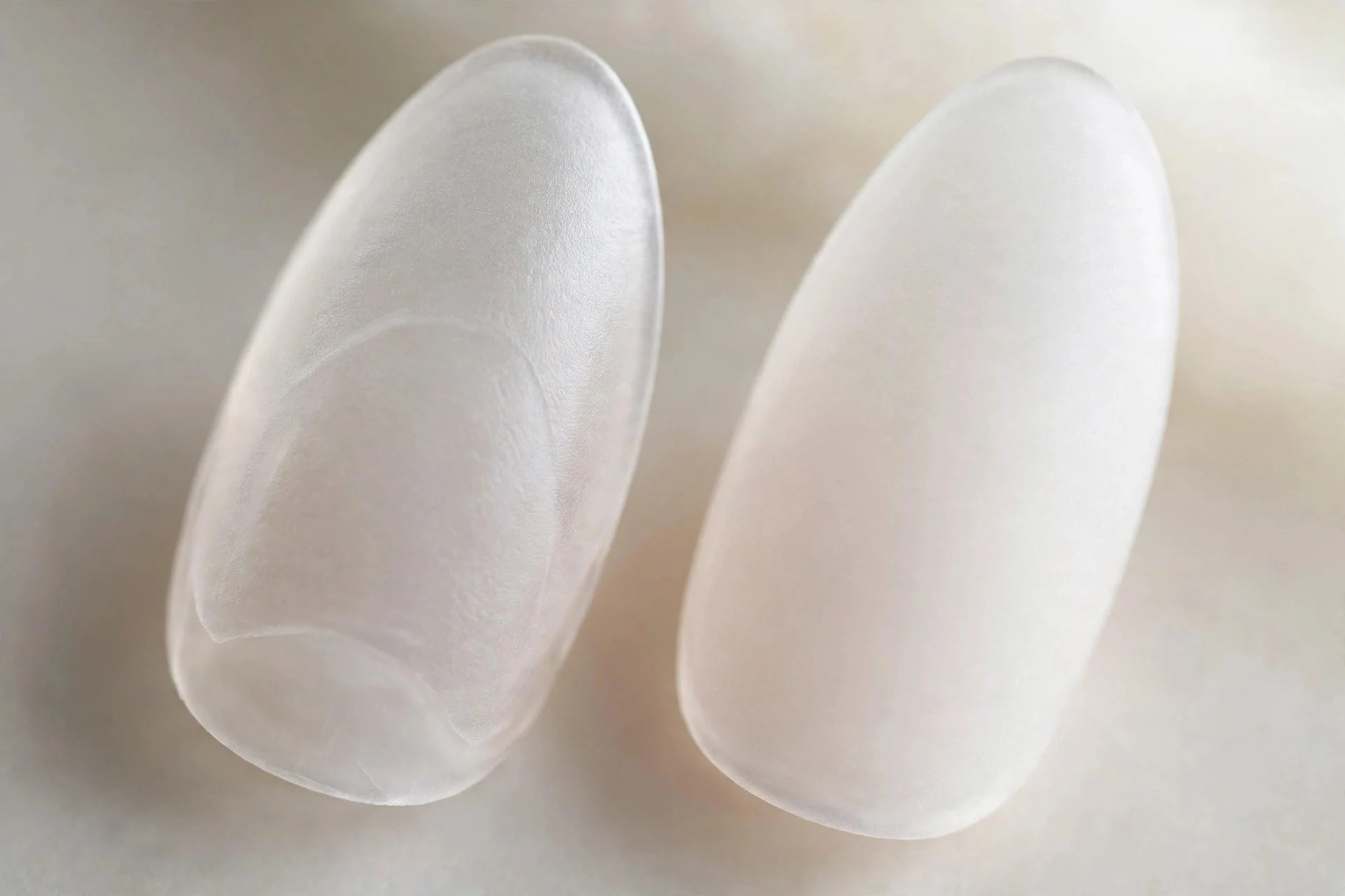 Extreme macro of two almond nails in sheer white frosted glass with etched-glass softness