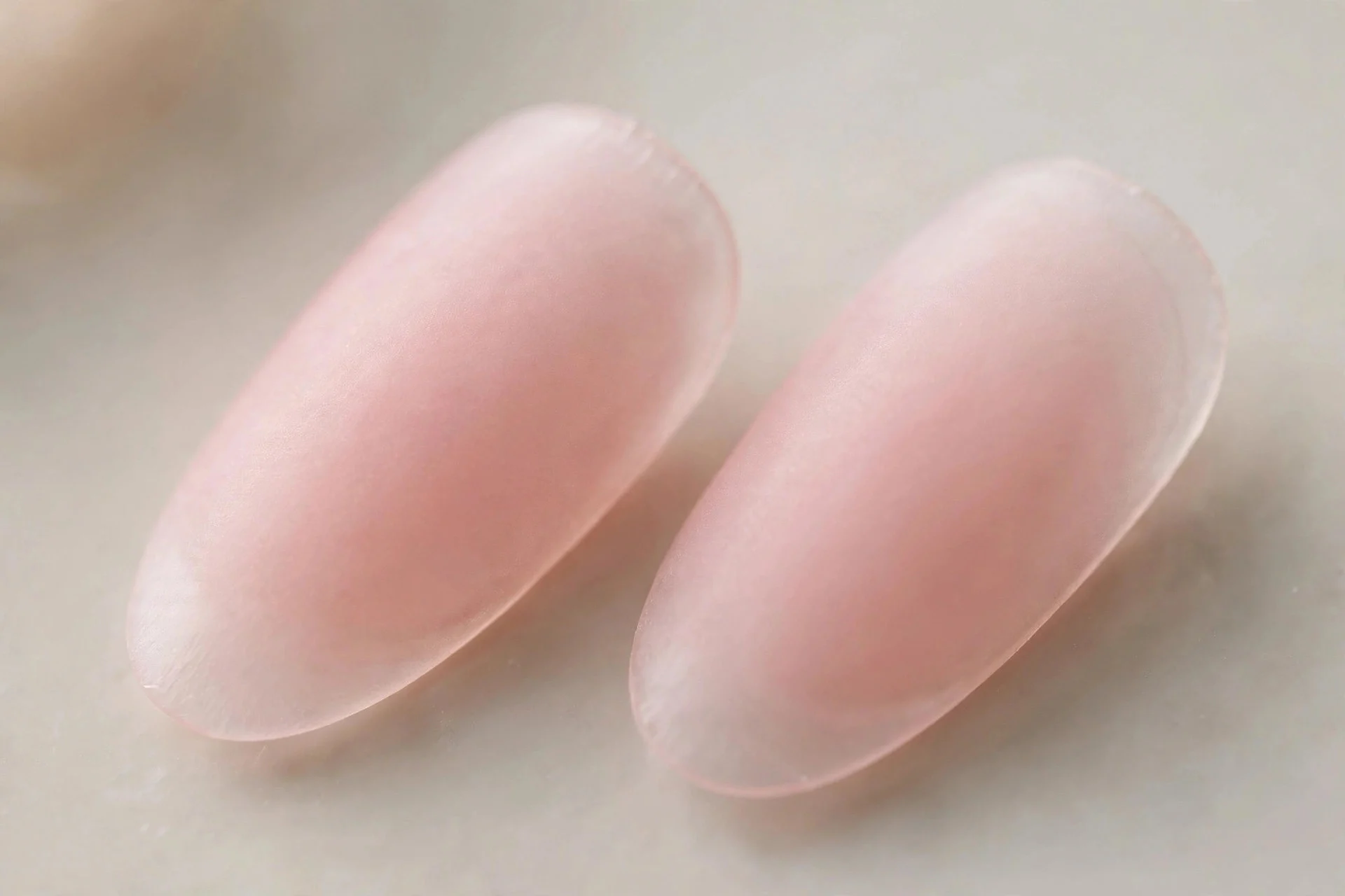 Extreme macro of two almond nails in blush-pink frosted glass with velvet matte finish