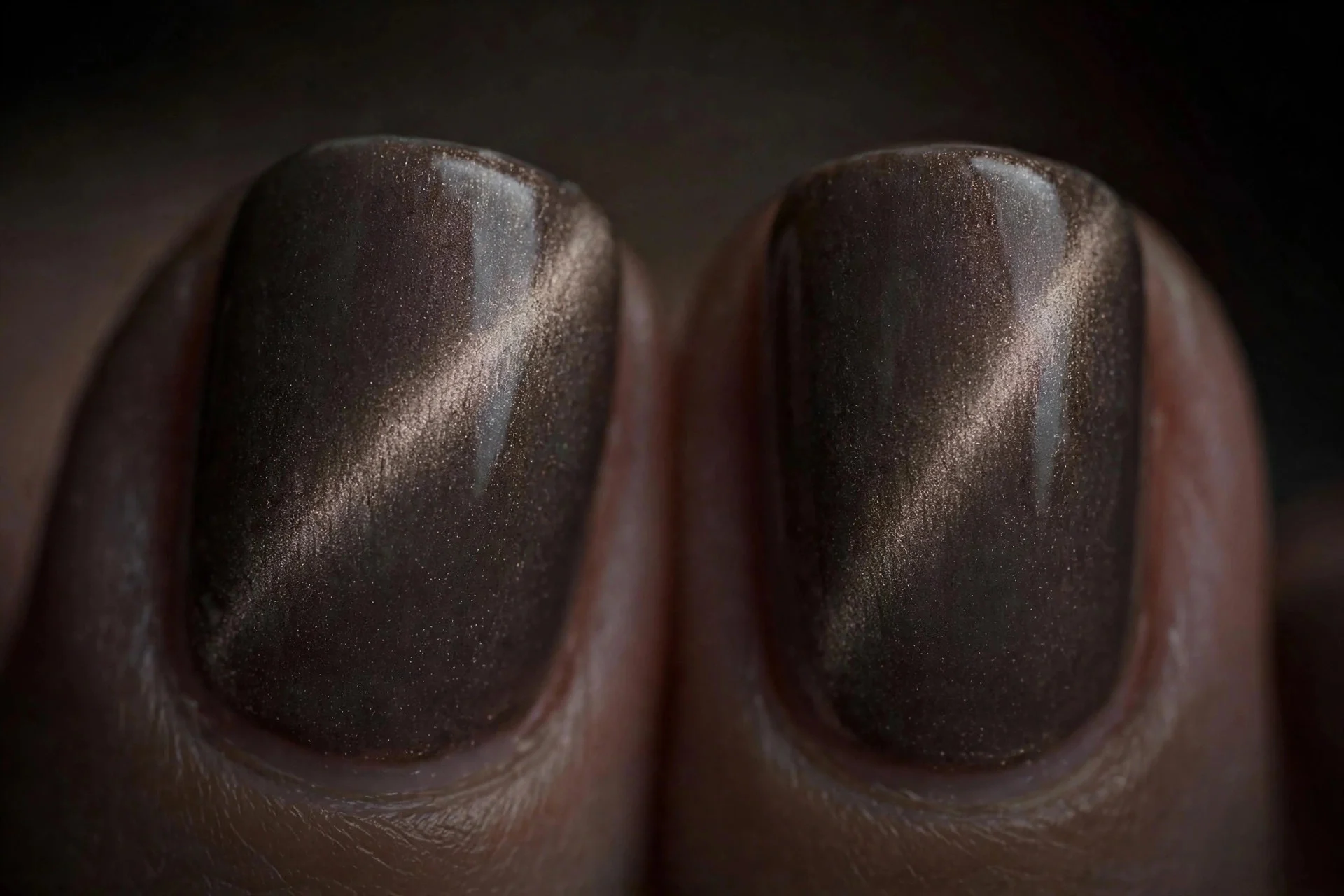 Extreme macro of two short fingernails in smoky taupe cat-eye gel with a subtle magnetic ribbon, understated dark neutral