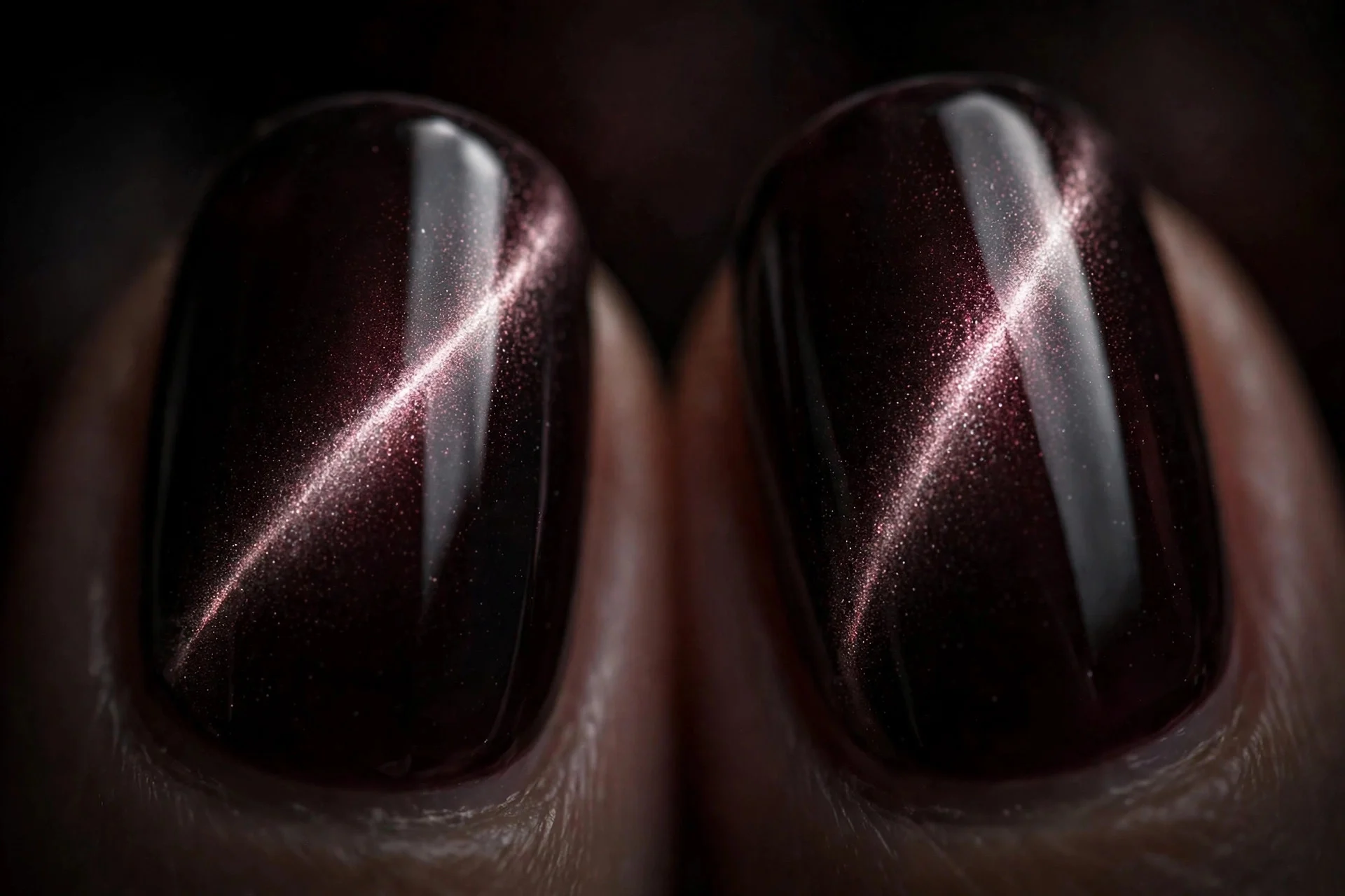 Extreme macro of two fingernails in black cherry cat-eye gel with a glassy reflective light band, decadent dark shine