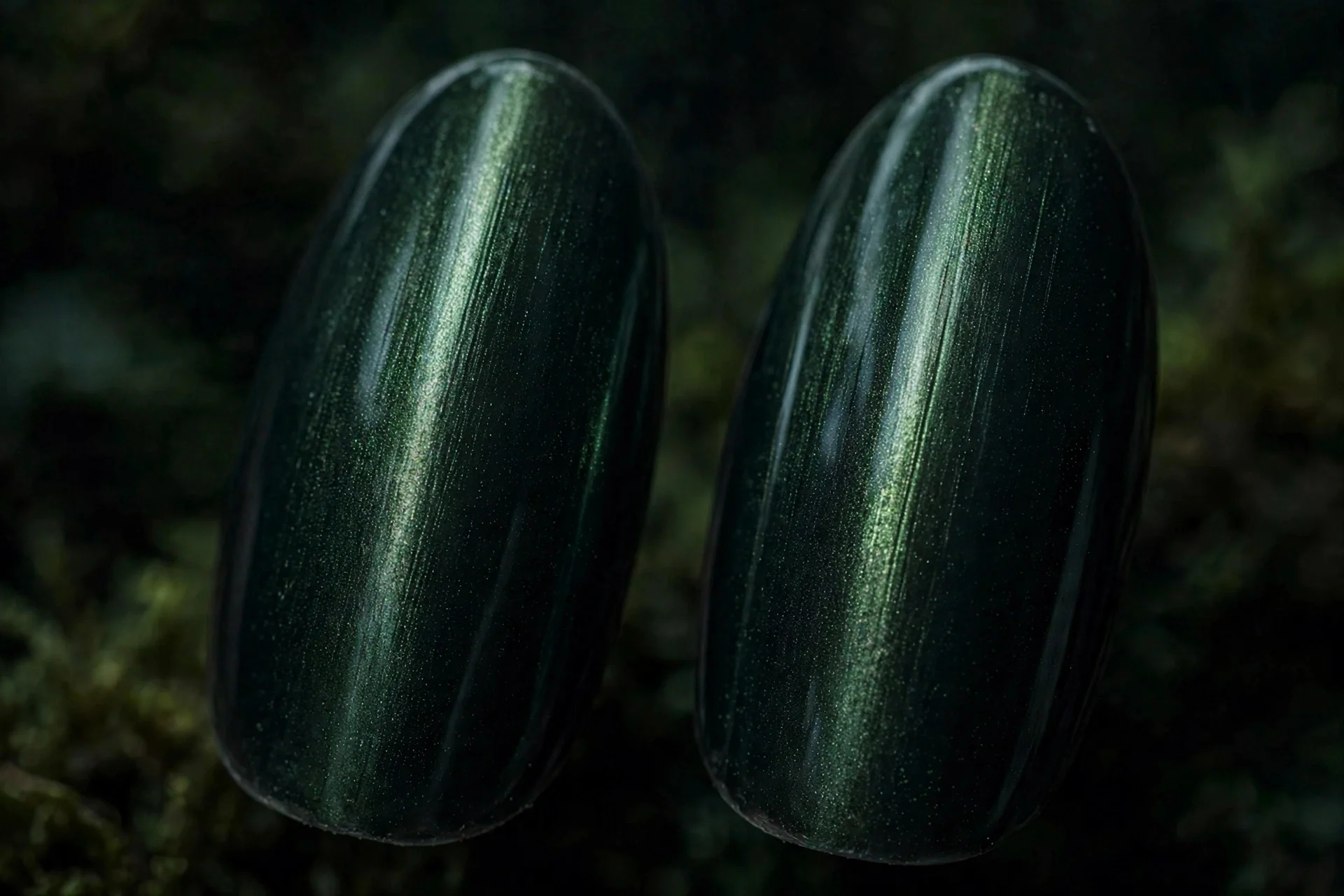 Extreme macro of two almond fingernails in midnight forest cat-eye gel with a narrow mysterious light band, near-black green