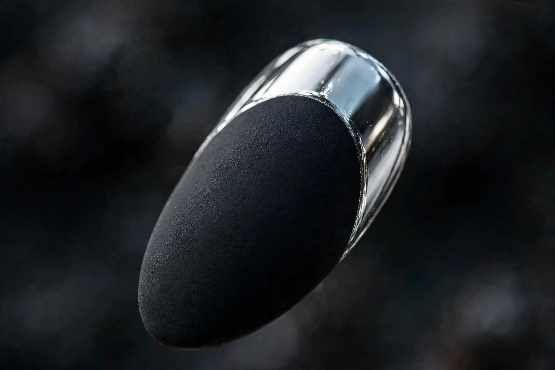 Almond fingernail with matte black base and silver chrome French tip, dark moody background