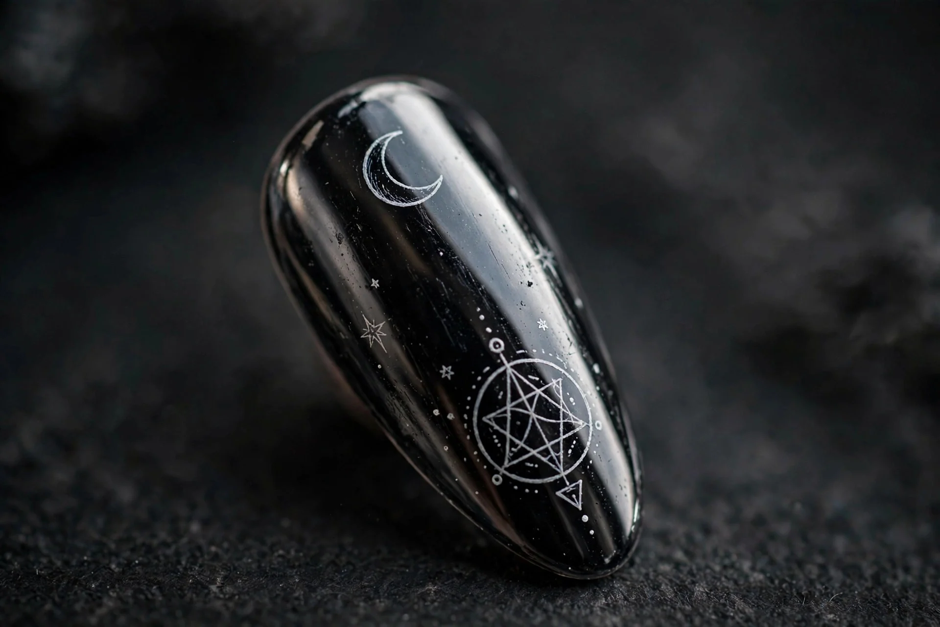 Almond fingernail in black mirror chrome with hand-painted white moon and sigil line art, dark background