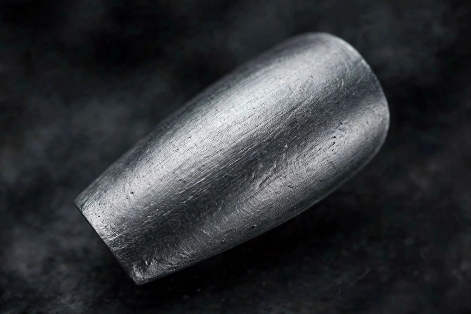 Short coffin fingernail in graphite grey brushed chrome, industrial matte-shine finish, dark background