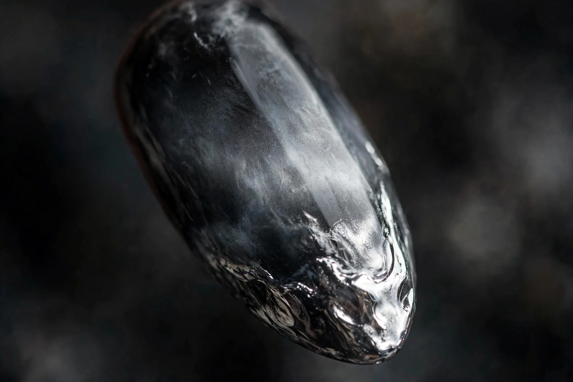 Almond fingernail with smoky grey-to-black gradient and silver storm-cloud chrome shine, dark background